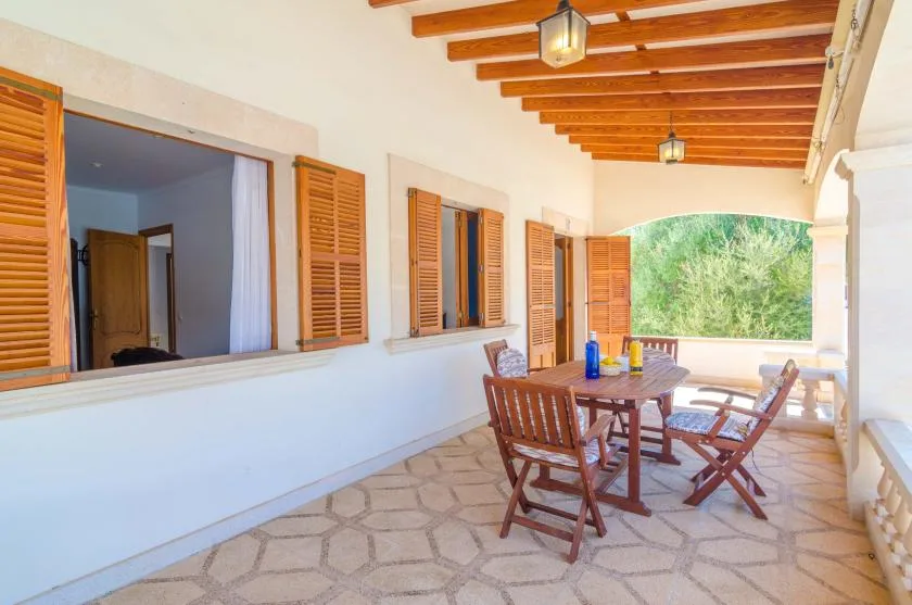 A covered outdoor dining area with a wooden table and seating.