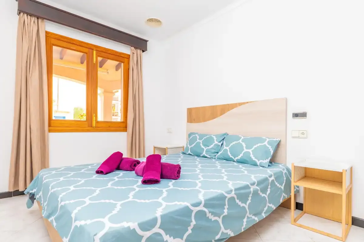 A bedroom with a bed covered in blue patterned bedding and a window.