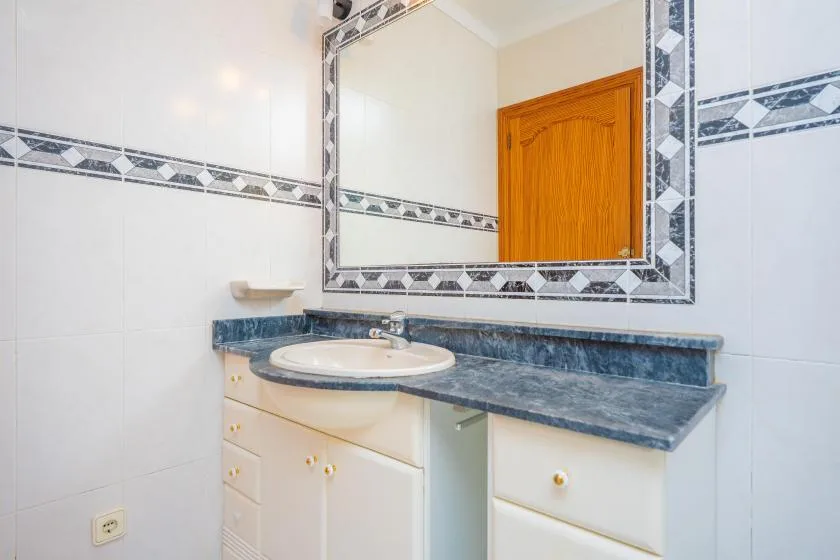 A bathroom vanity with a sink sits beneath a large wall mirror.