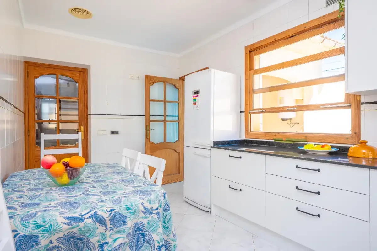 A bright kitchen with white cabinets, a countertop, and a dining table.