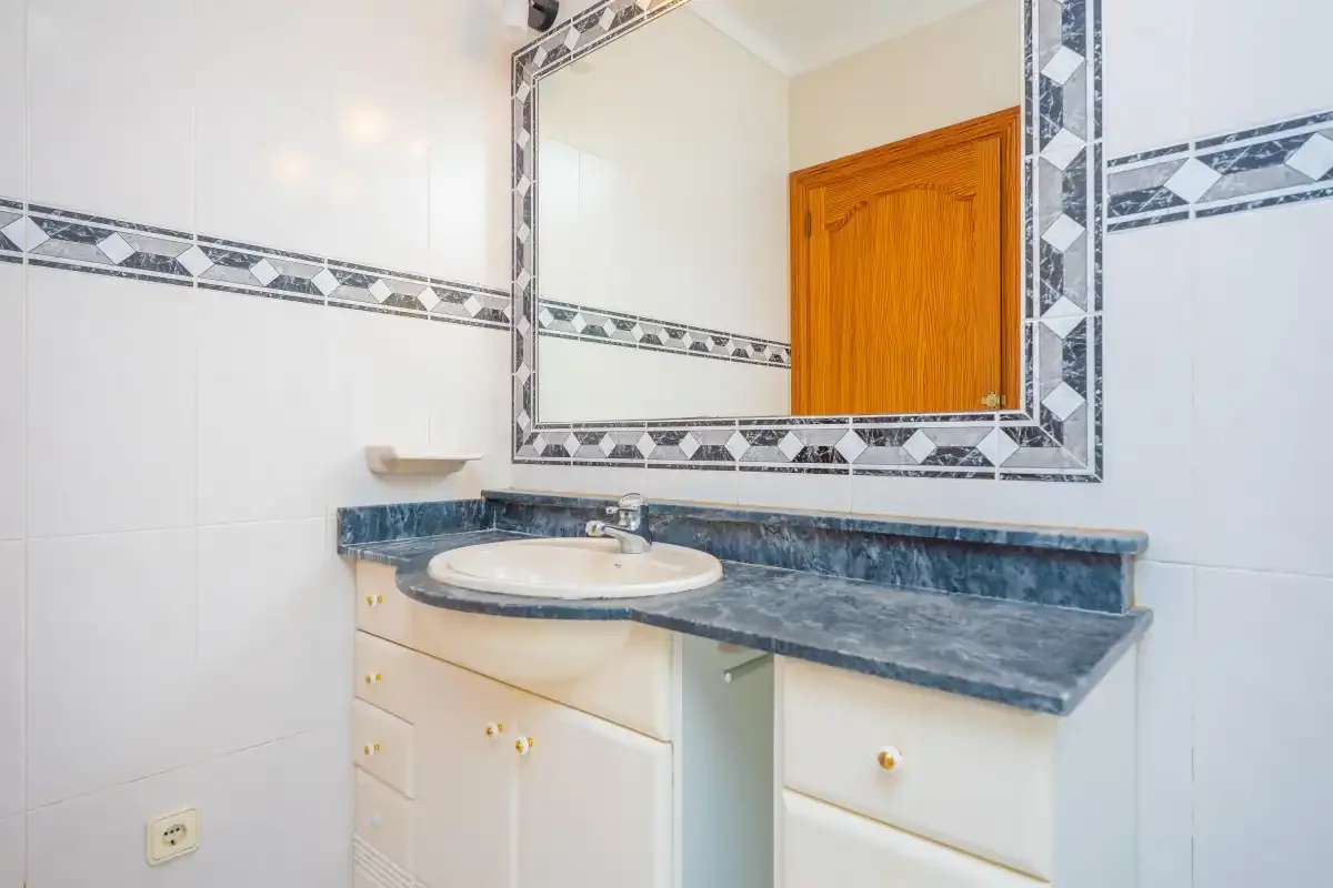 A bathroom vanity with a sink and a large wall mirror.
