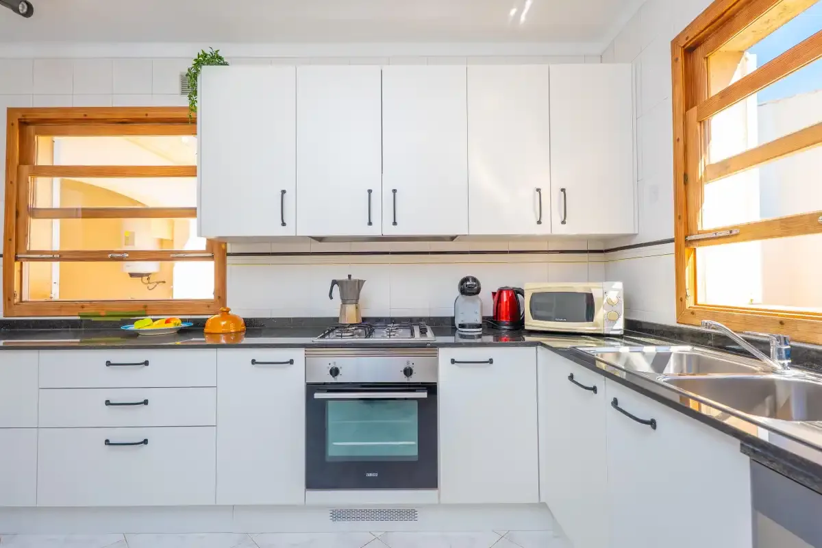 A bright kitchen with white cabinets, a stove, and a countertop.