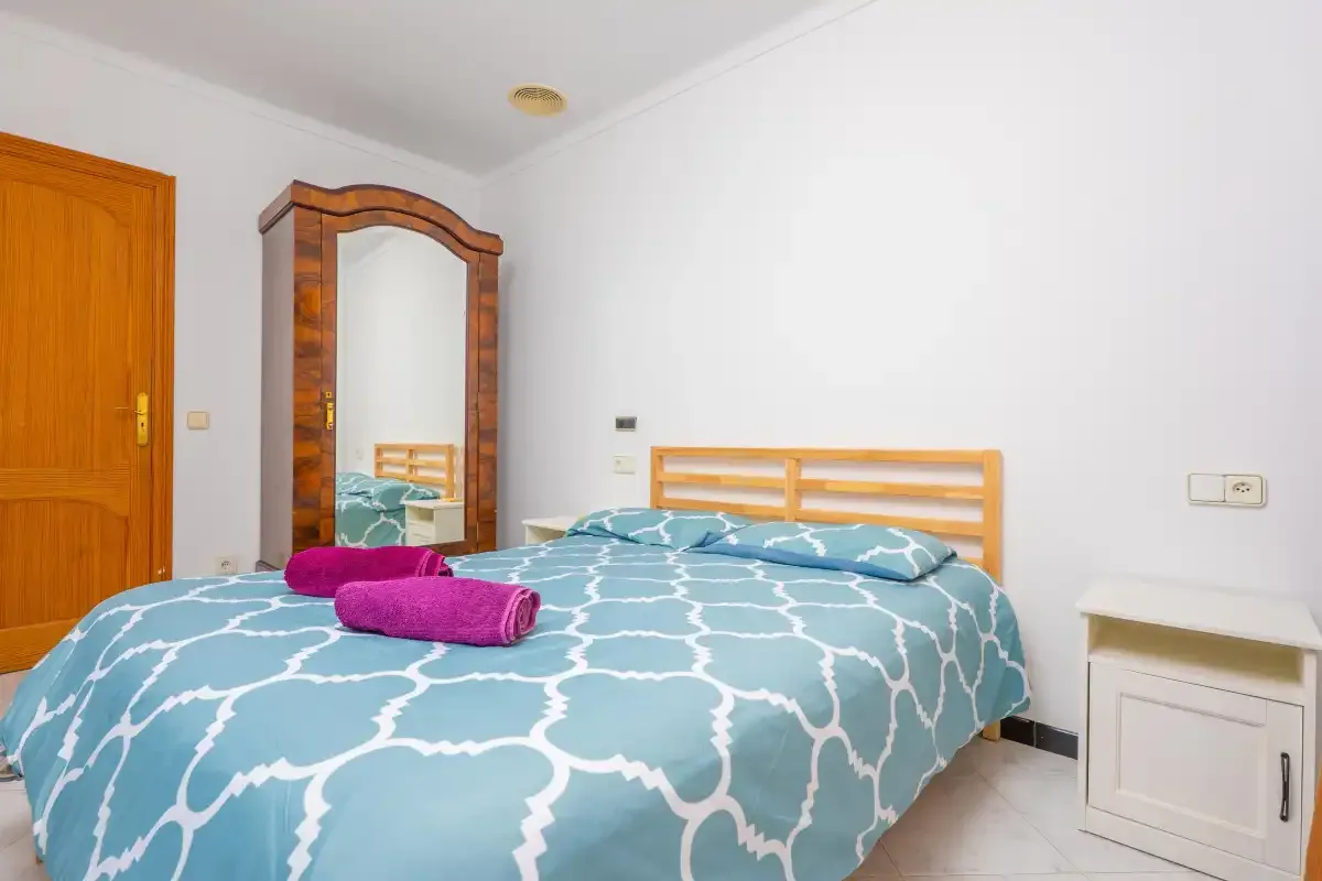 A bedroom with a bed covered in blue patterned bedding.
