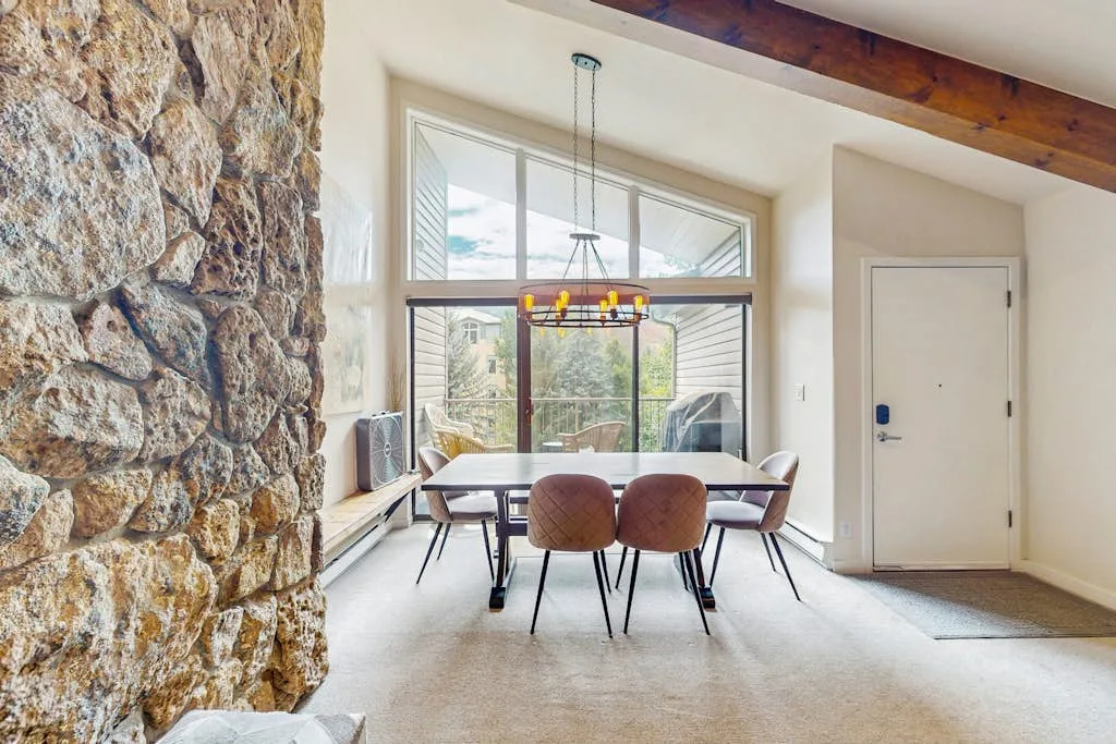 A dining area with a table and chairs beside large windows.