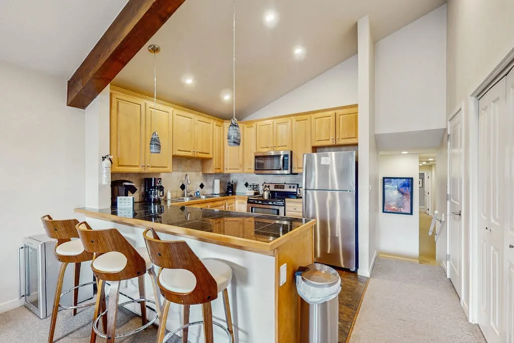 Una cocina luminosa con gabinetes de madera, una isla central y electrodomésticos de acero inoxidable.