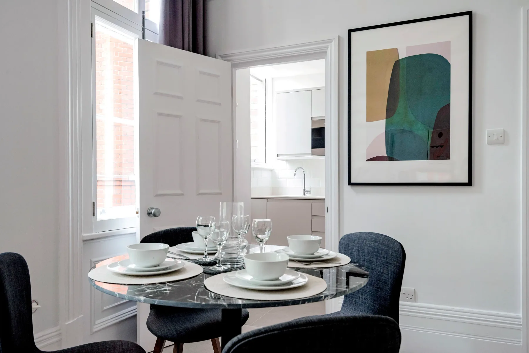 Un comedor con la mesa puesta junto a una puerta abierta.