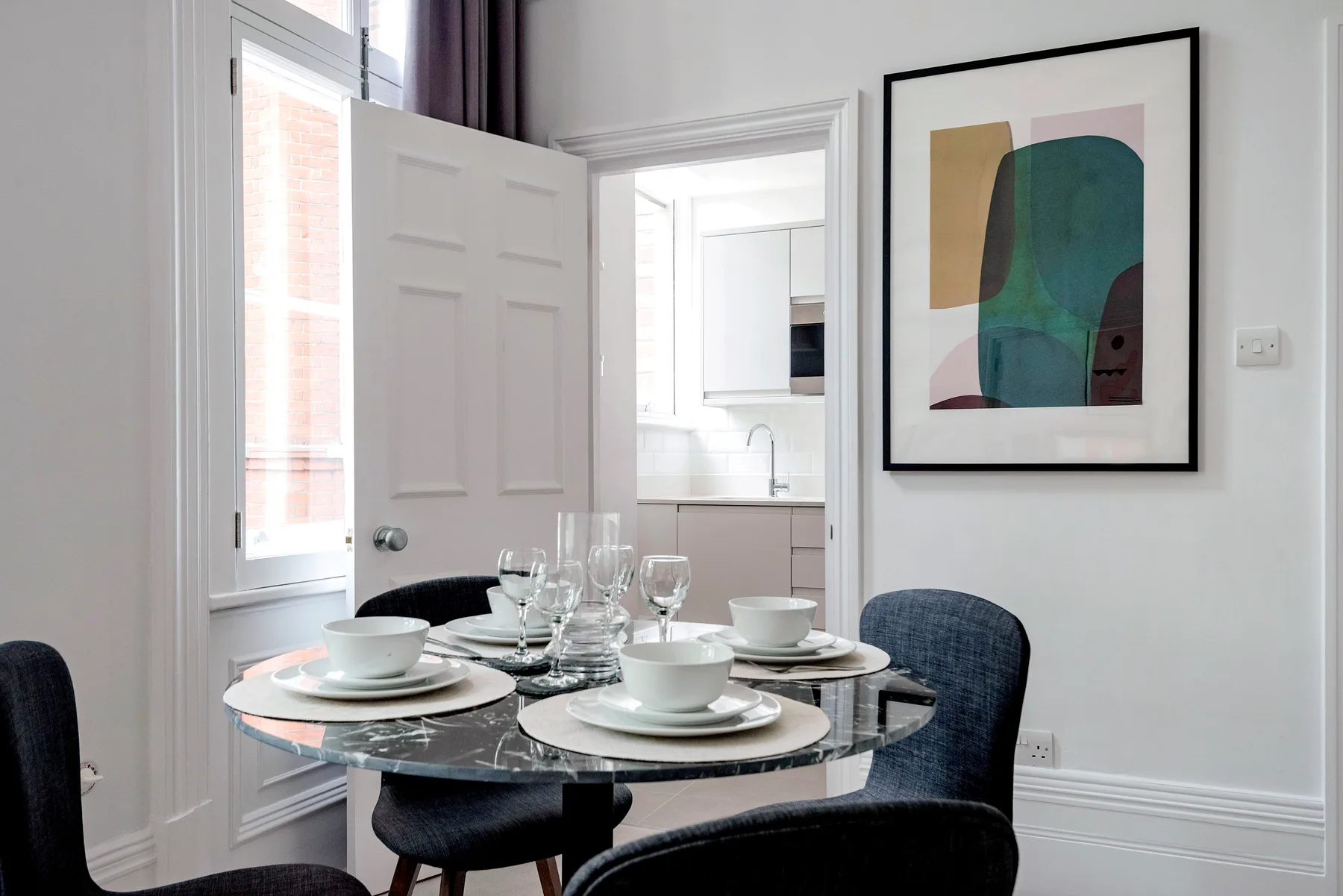 Un comedor con la mesa puesta y una obra abstracta enmarcada en la pared.
