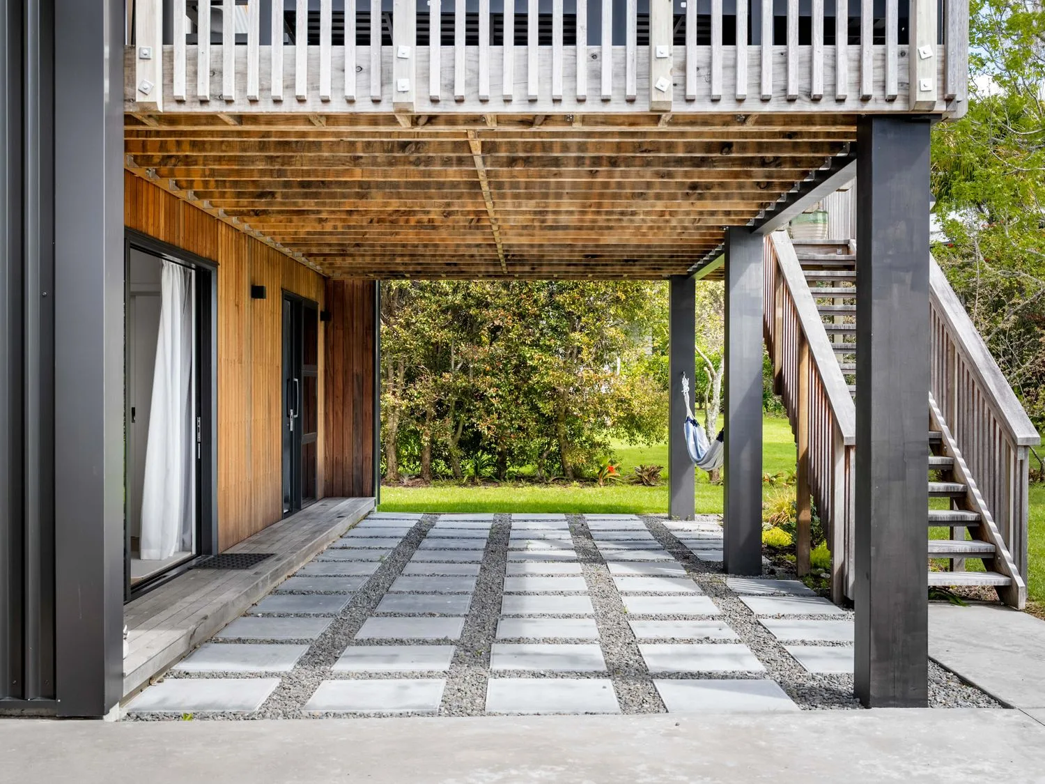 An outdoor area with a wooden deck and stairs at The Cove Escape - Cooks Beach