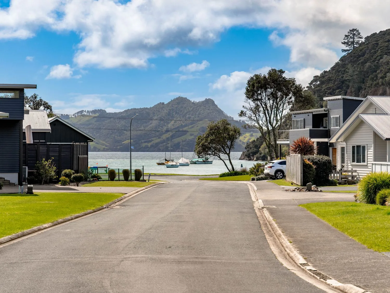 A view of houses and boats by the water at The Cove Escape - Cooks Beach