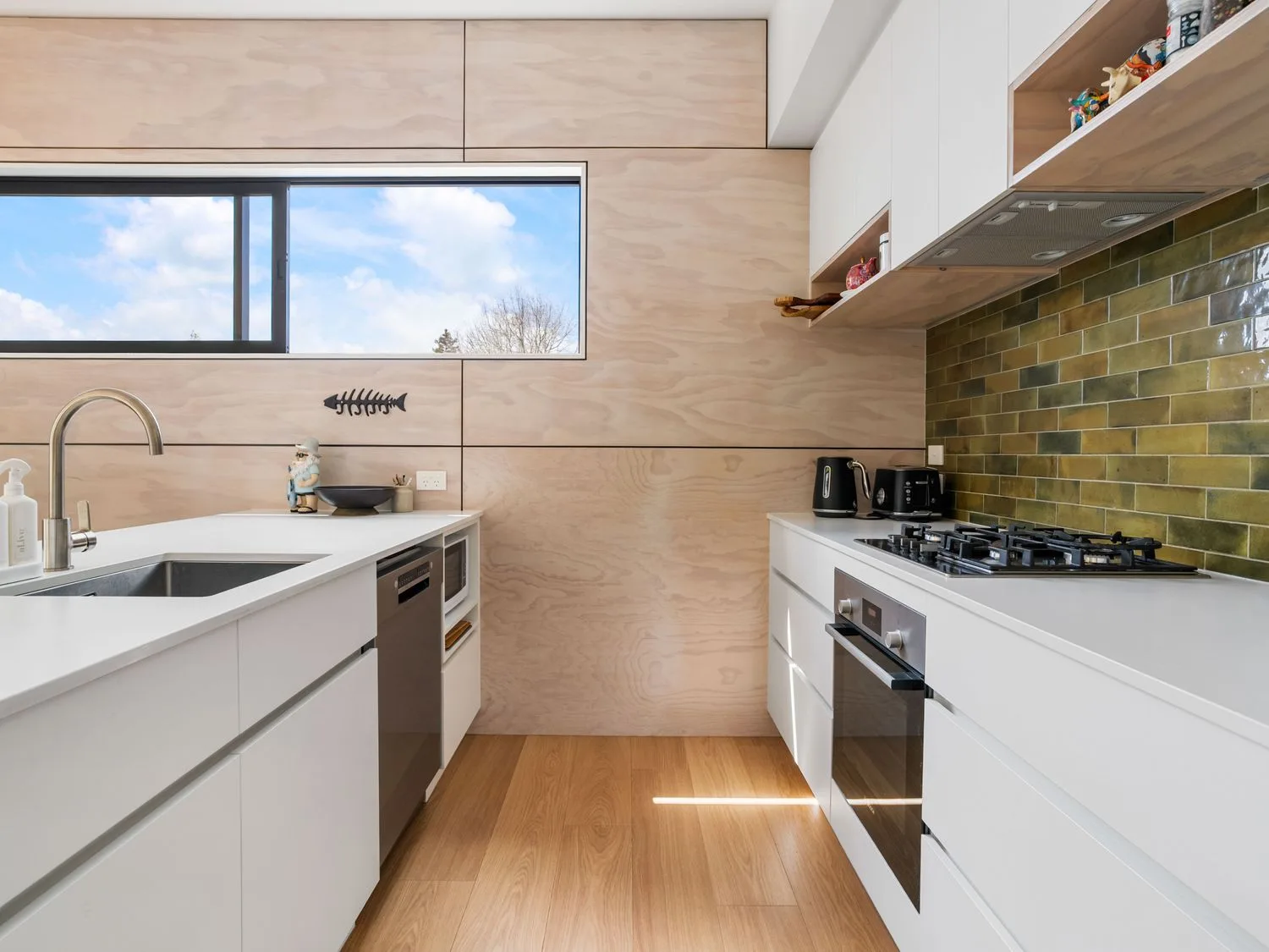 A kitchen with a sink, oven, and window at The Cove Escape - Cooks Beach
