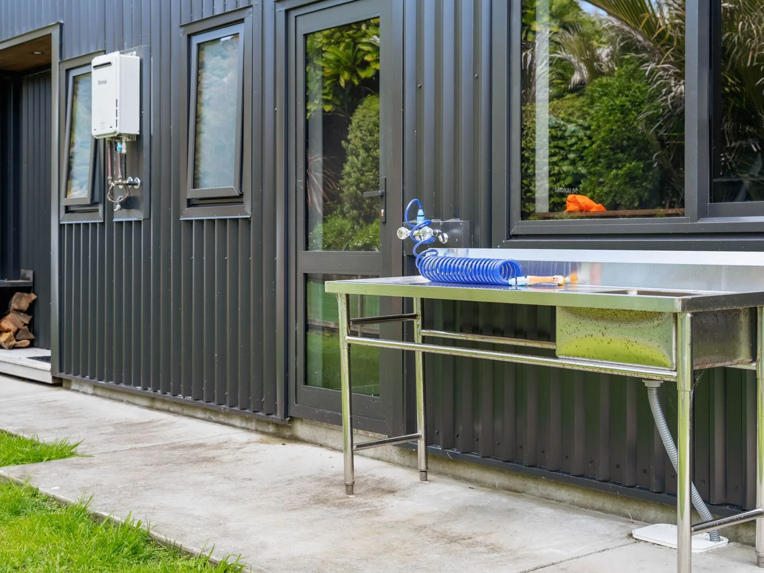 An outdoor area with a sink and water hose at The Cove Escape - Cooks Beach