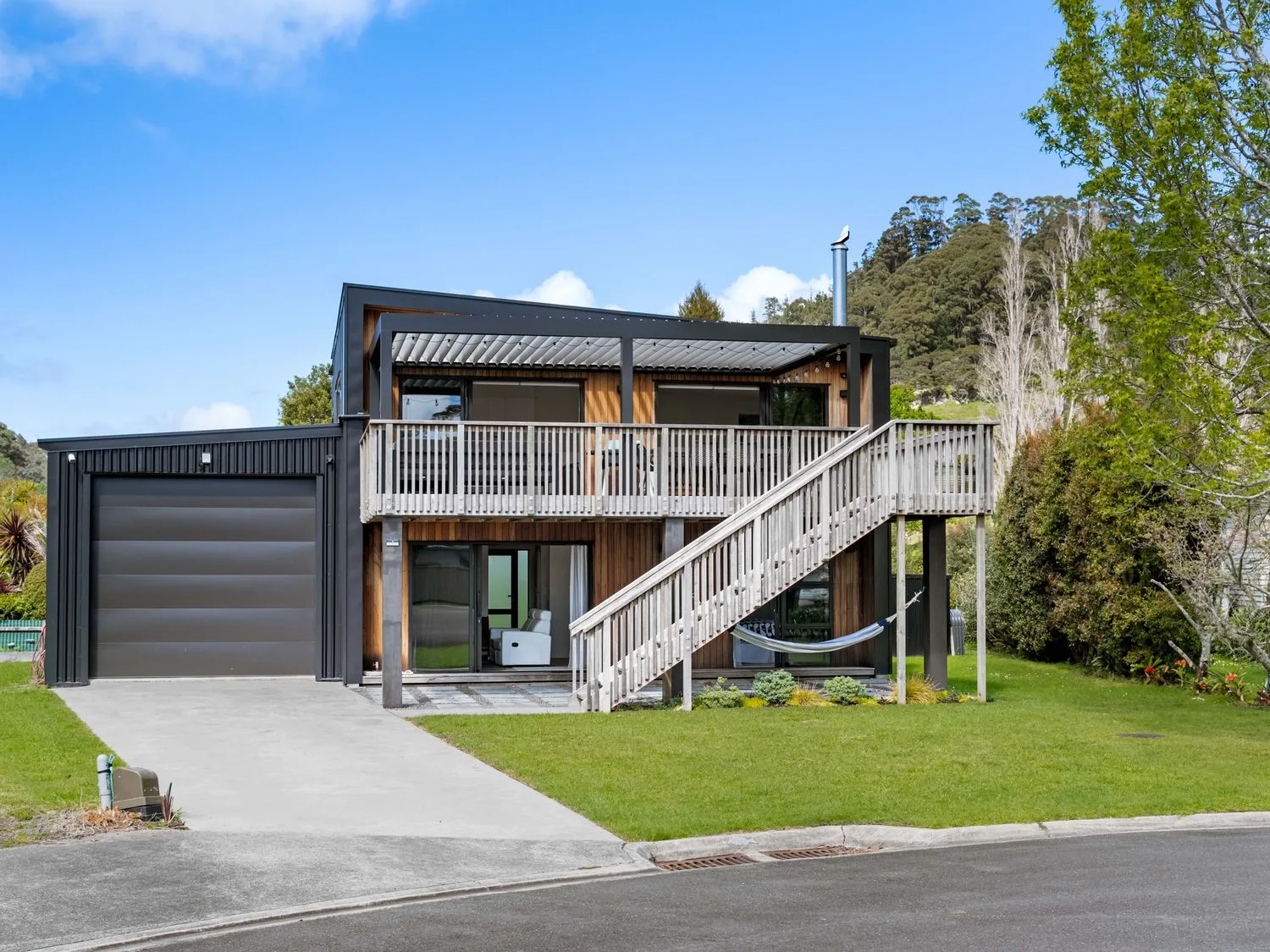 Una casa con garaje y terraza de madera en The Cove Escape - Cooks Beach