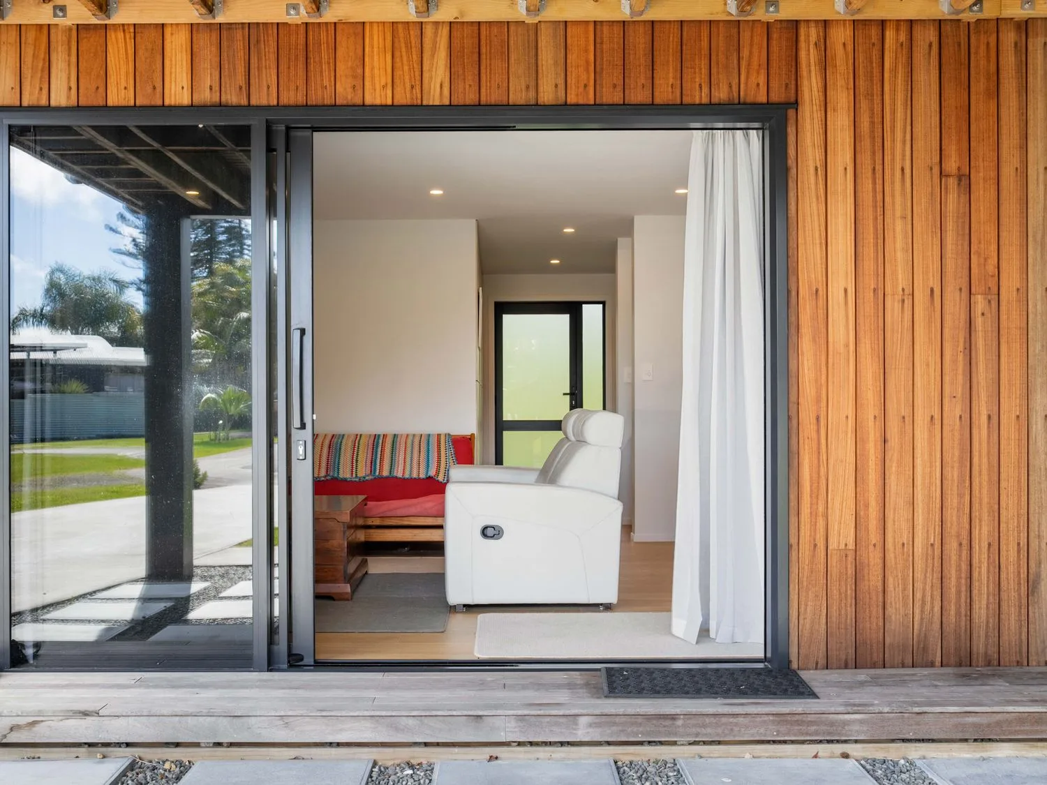 A living room with a sofa and chair at The Cove Escape - Cooks Beach