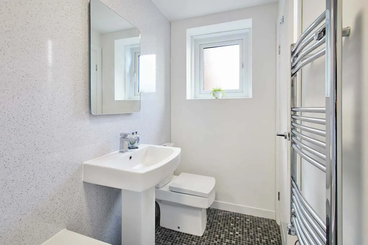 Un baño luminoso con lavabo, inodoro y ventana.