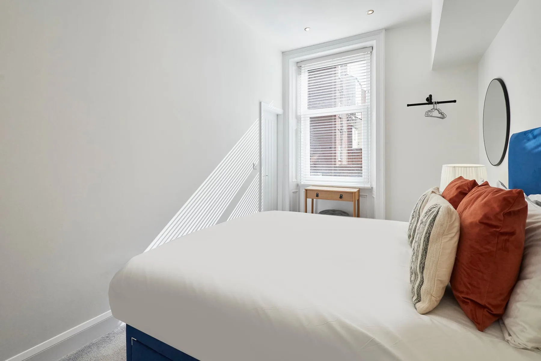Un dormitorio luminoso con una cama bien arreglada junto a una ventana.