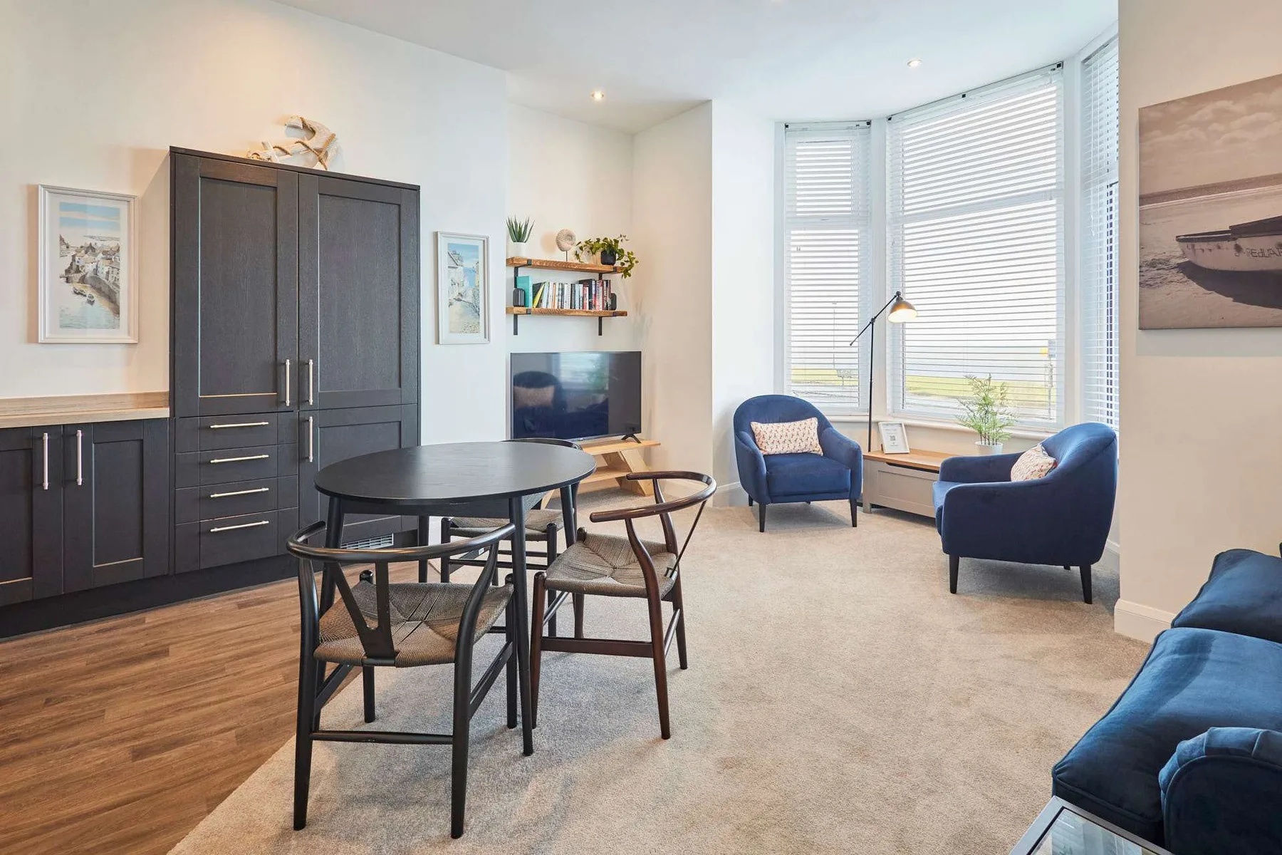 Una sala luminosa con mesa de comedor y asientos junto a grandes ventanas.