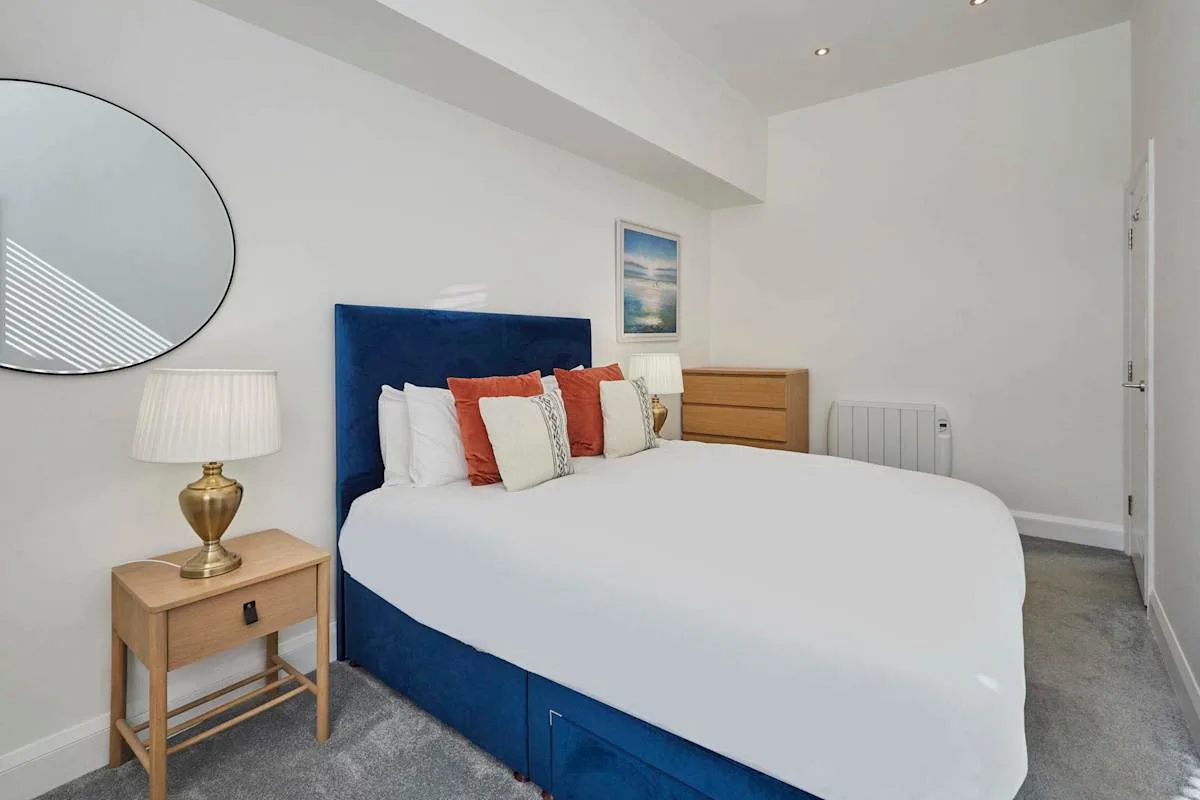 Un dormitorio luminoso con una cama bien arreglada y mesitas de noche.
