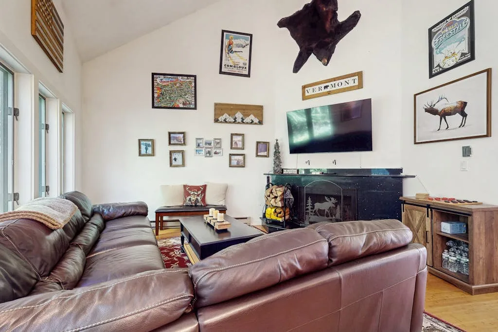 A living room with leather seating, a television, and framed artwork.