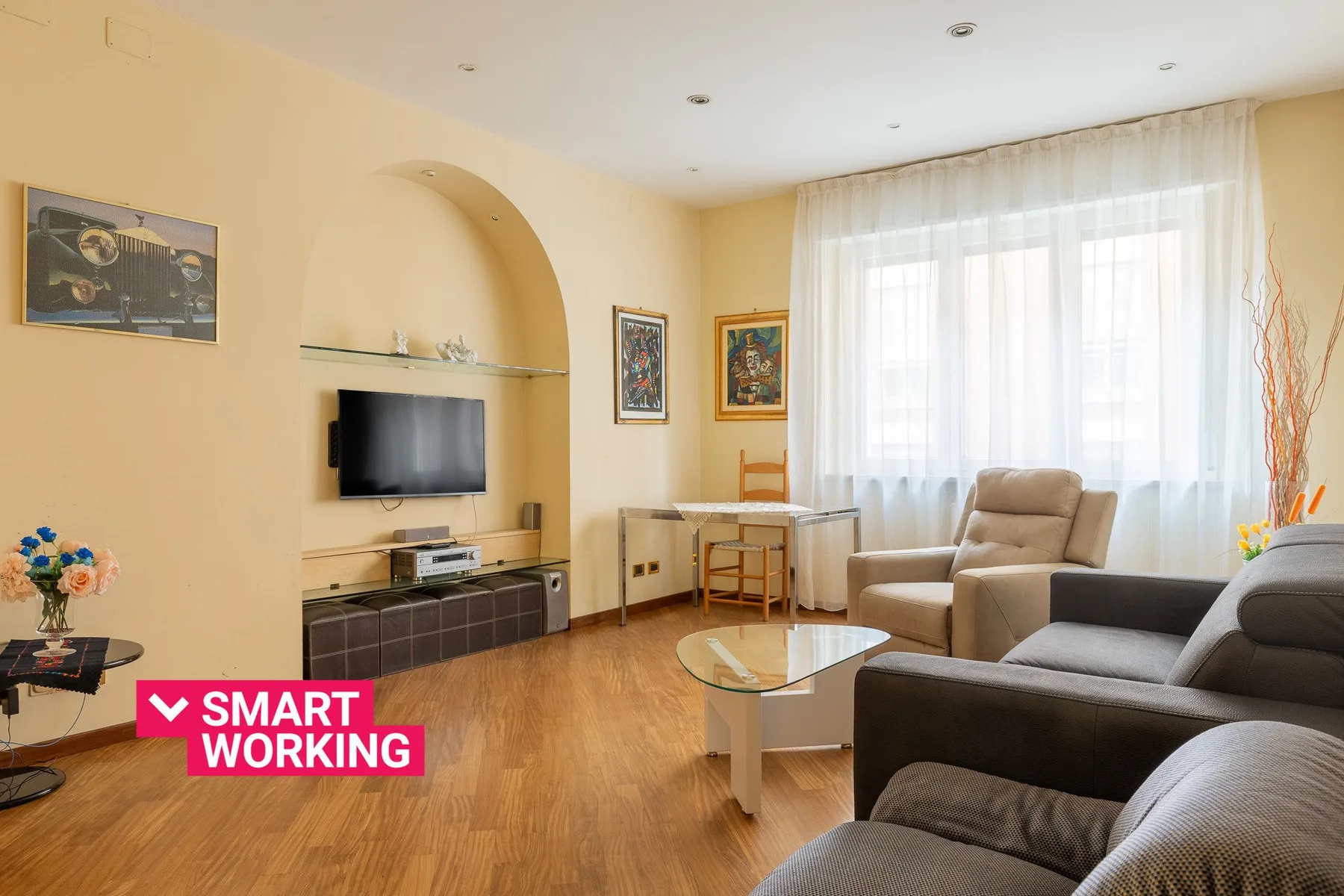 Una sala de estar con asientos, un televisor y una ventana luminosa.