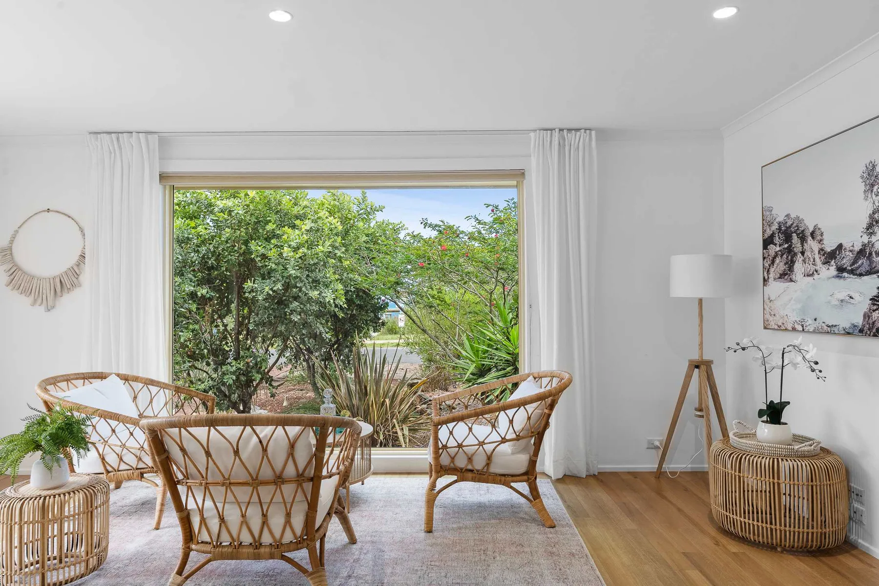 A bright sitting area with woven seating facing a large window overlooking greenery.