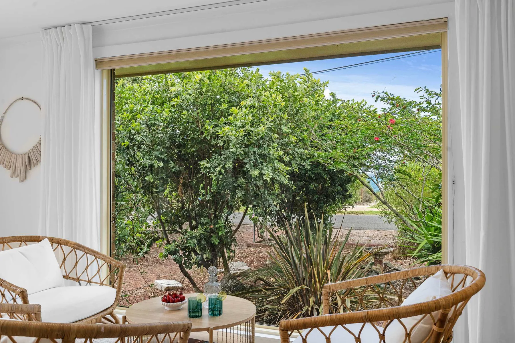 A bright sitting area opens onto a garden through a wide window.