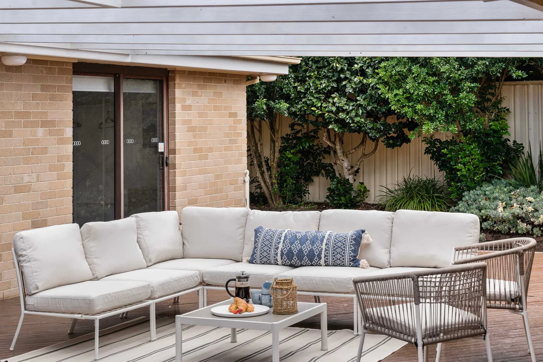 A covered outdoor seating area with a sectional and low table.