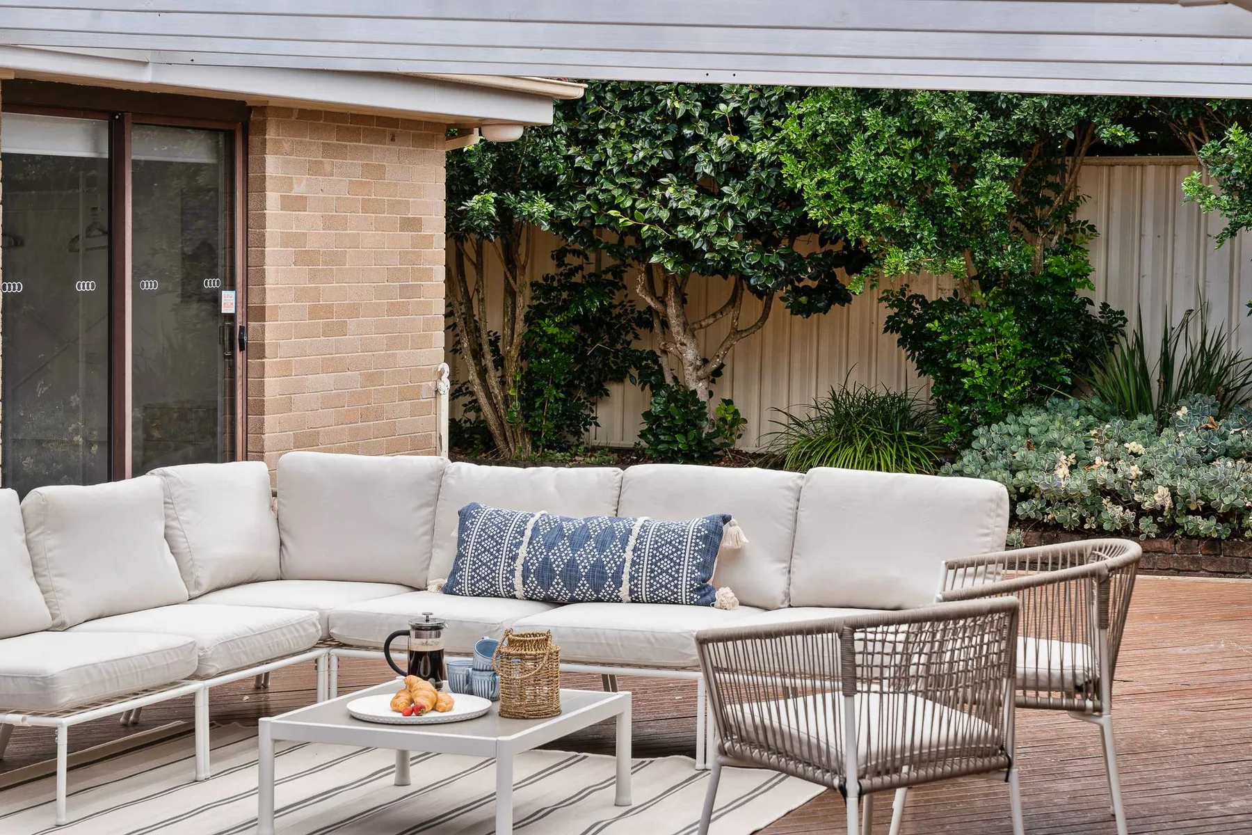 A covered outdoor seating area with a sectional and low table.