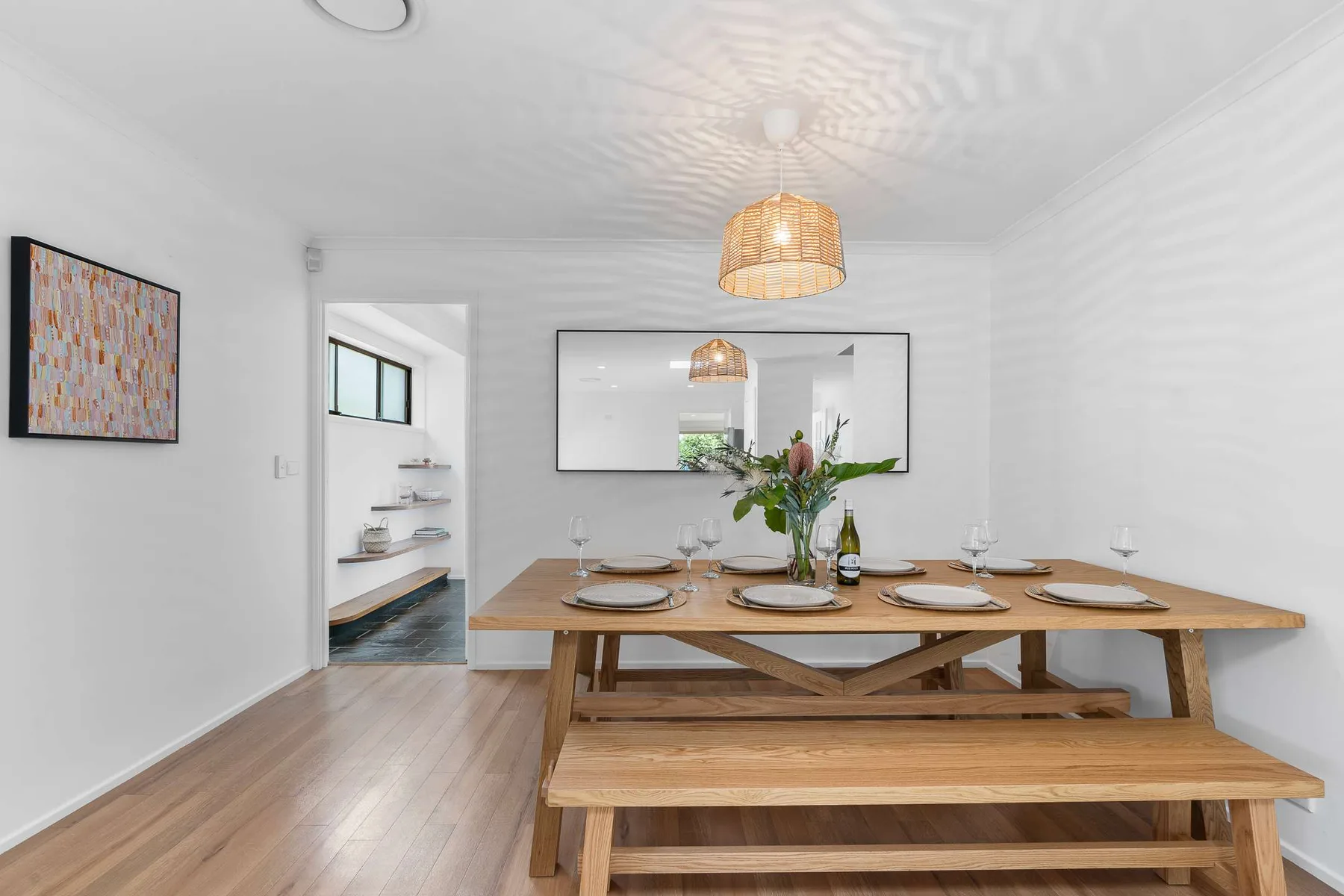 A dining area with a long wooden table and bench beneath pendant lights.