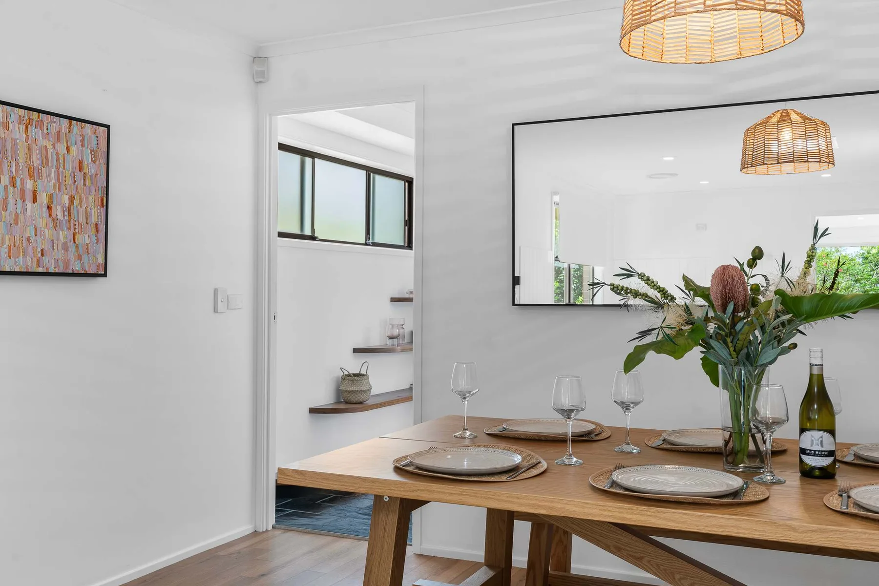 Dining area with a wooden table set with plates and glassware.