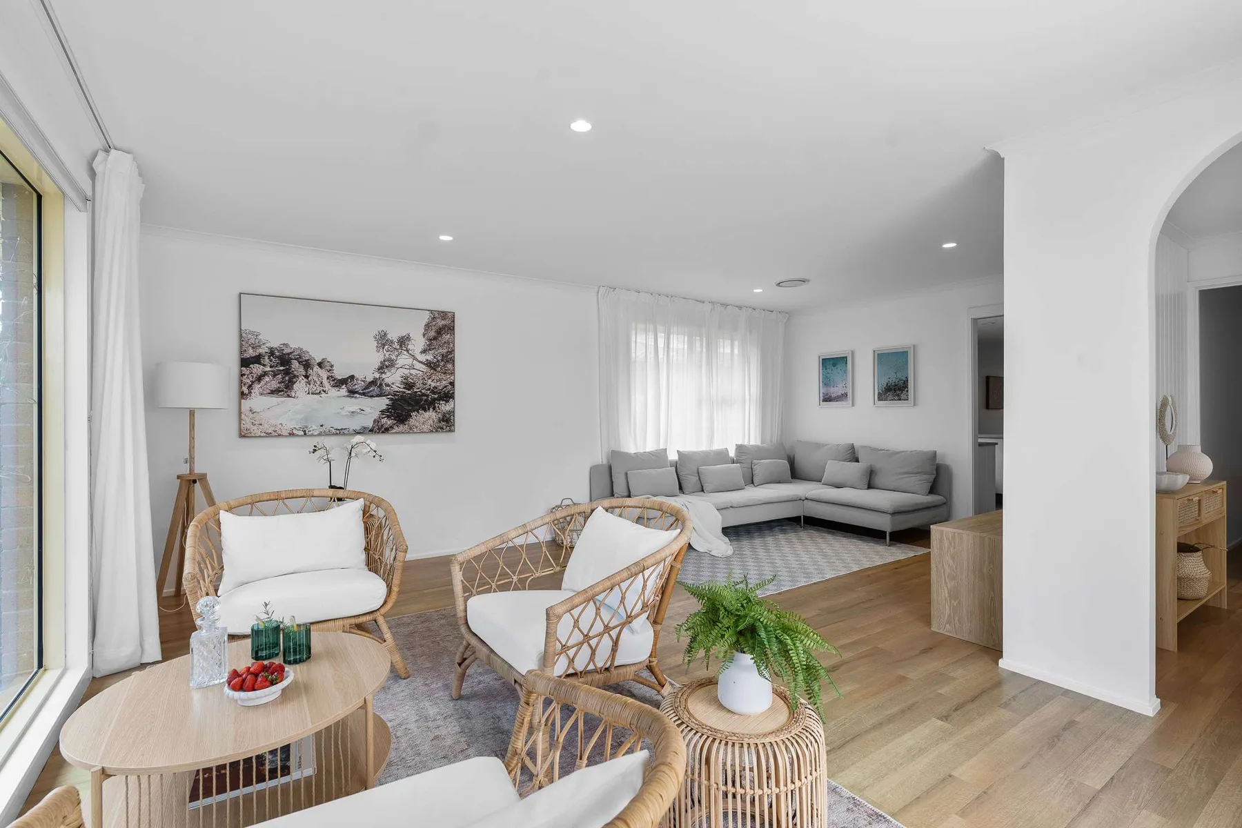 A bright living room with seating, a coffee table, and framed wall art.