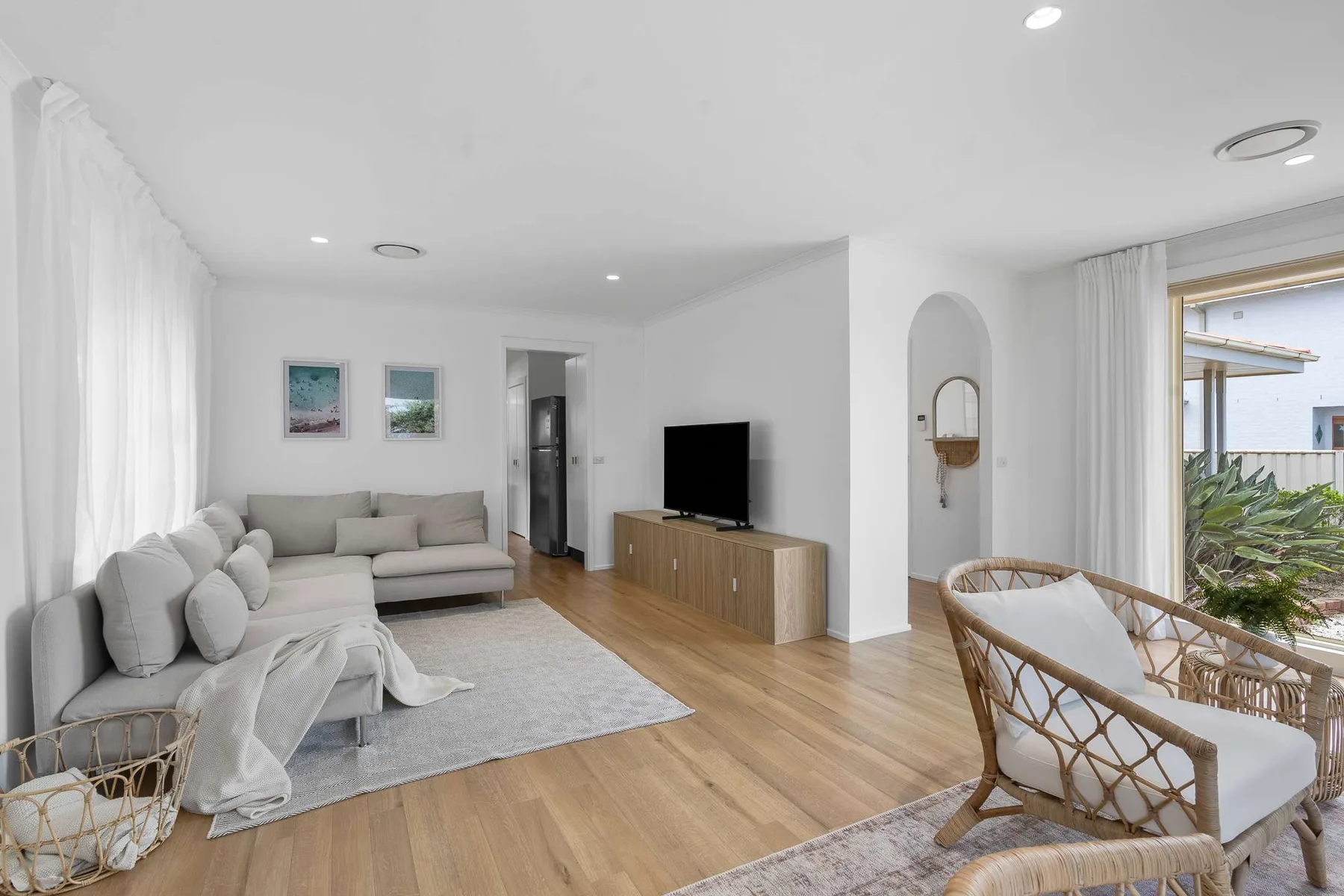 A bright living room with seating, a television, and large windows.