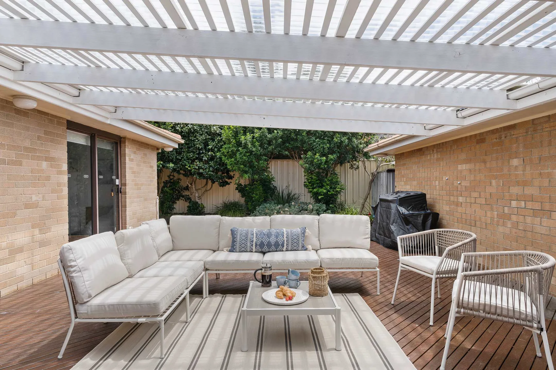 A covered patio with outdoor seating and a low table.