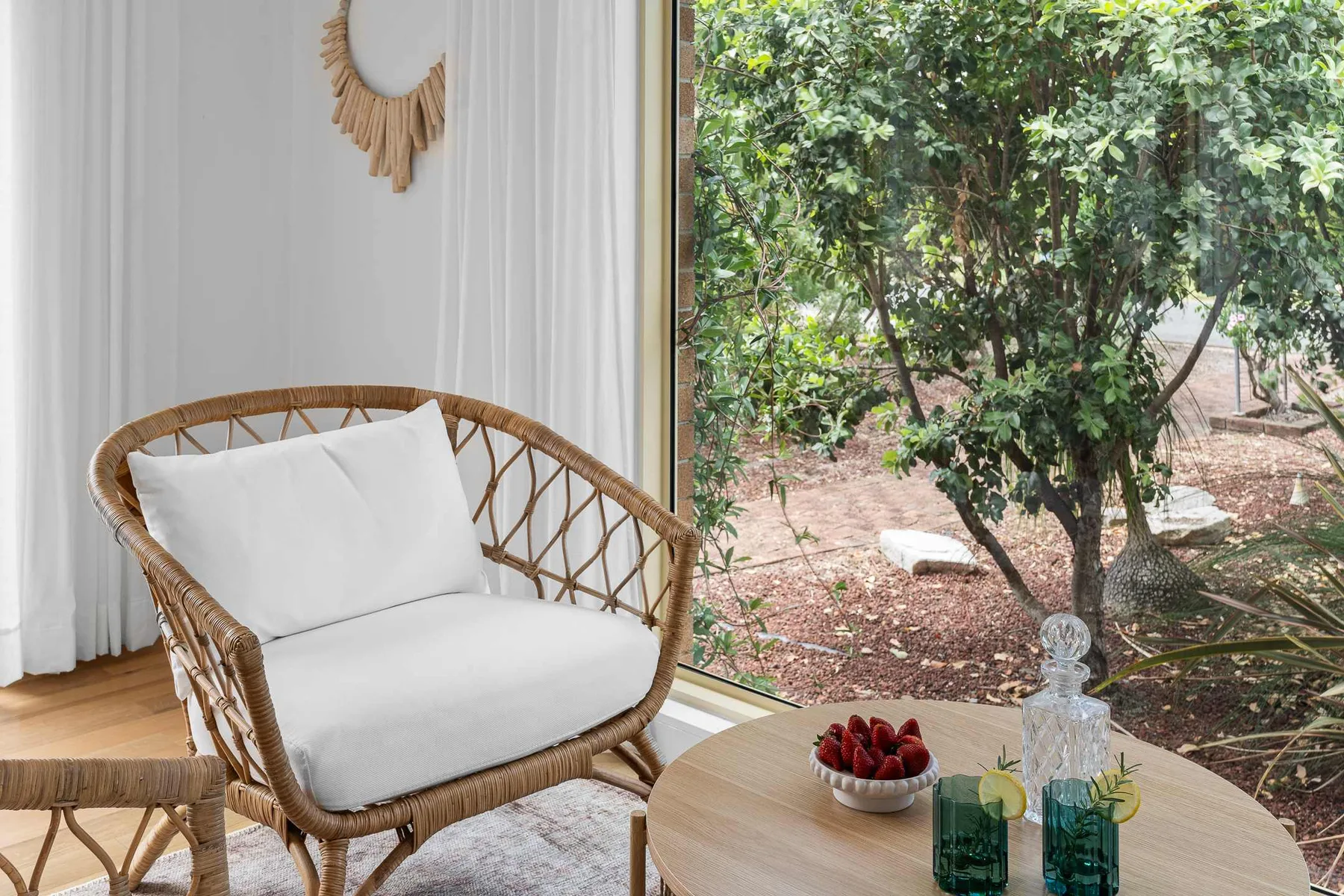 A seating area by a large window overlooks a leafy garden.