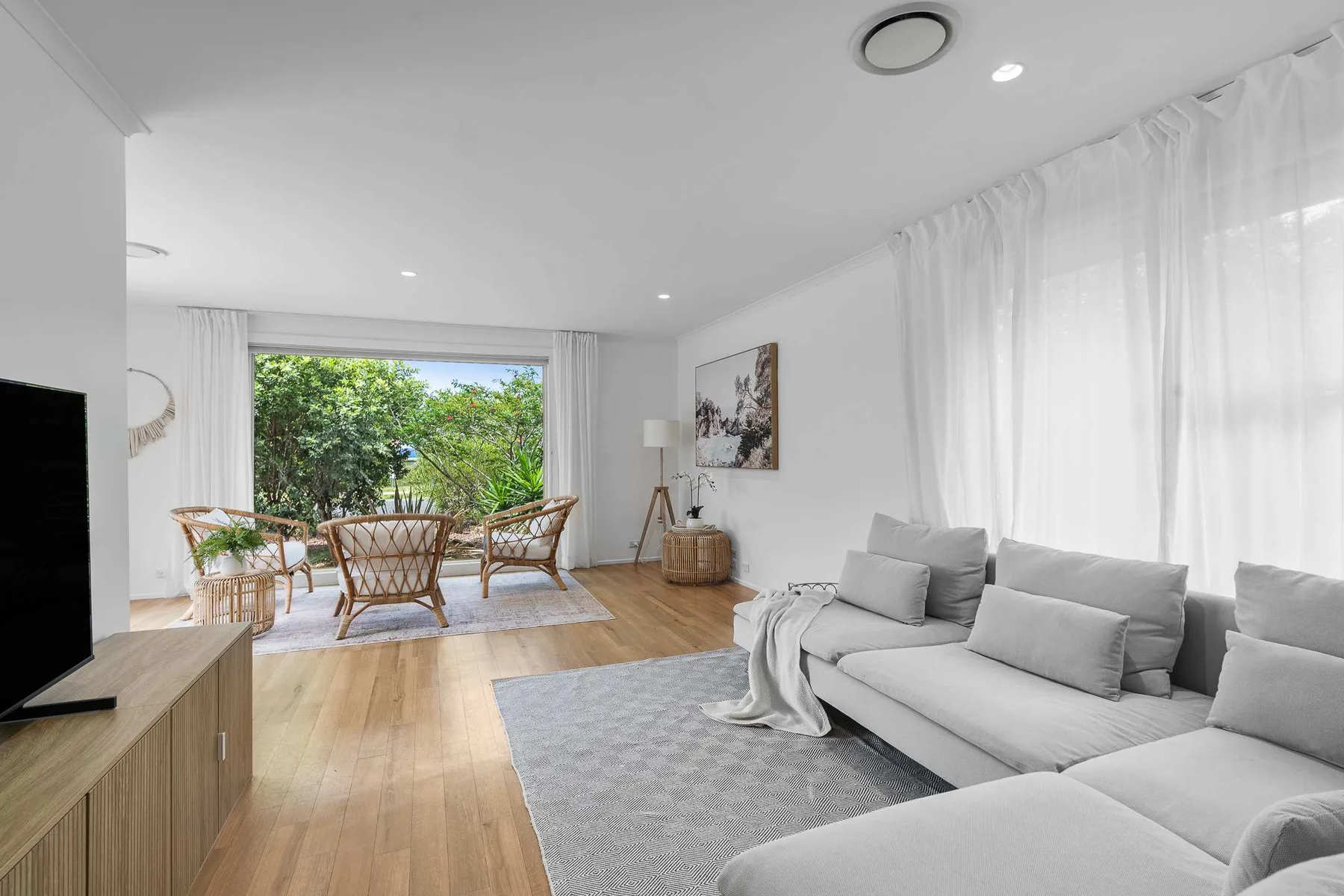 Bright living room with seating and a dining area beside large windows.