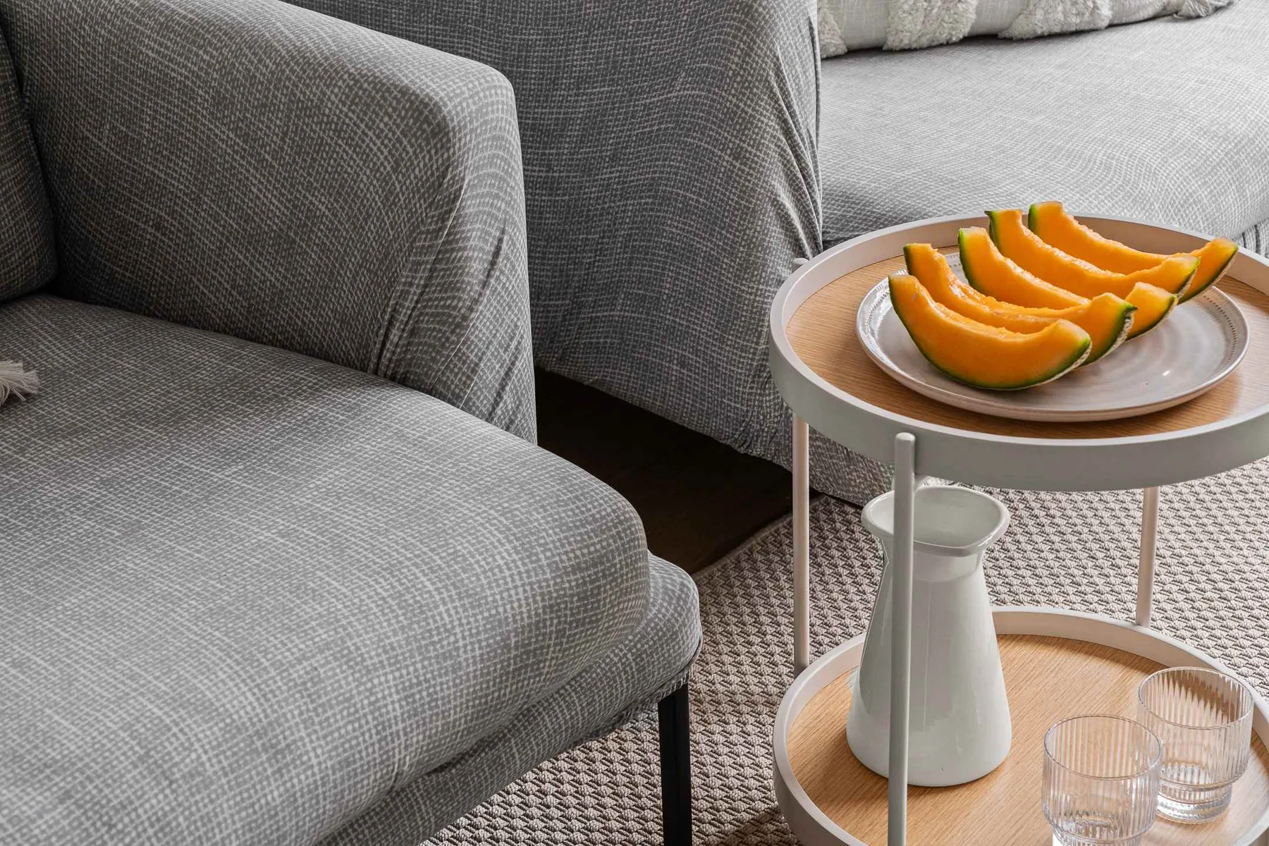 A living room seating area with a small table holding sliced melon.