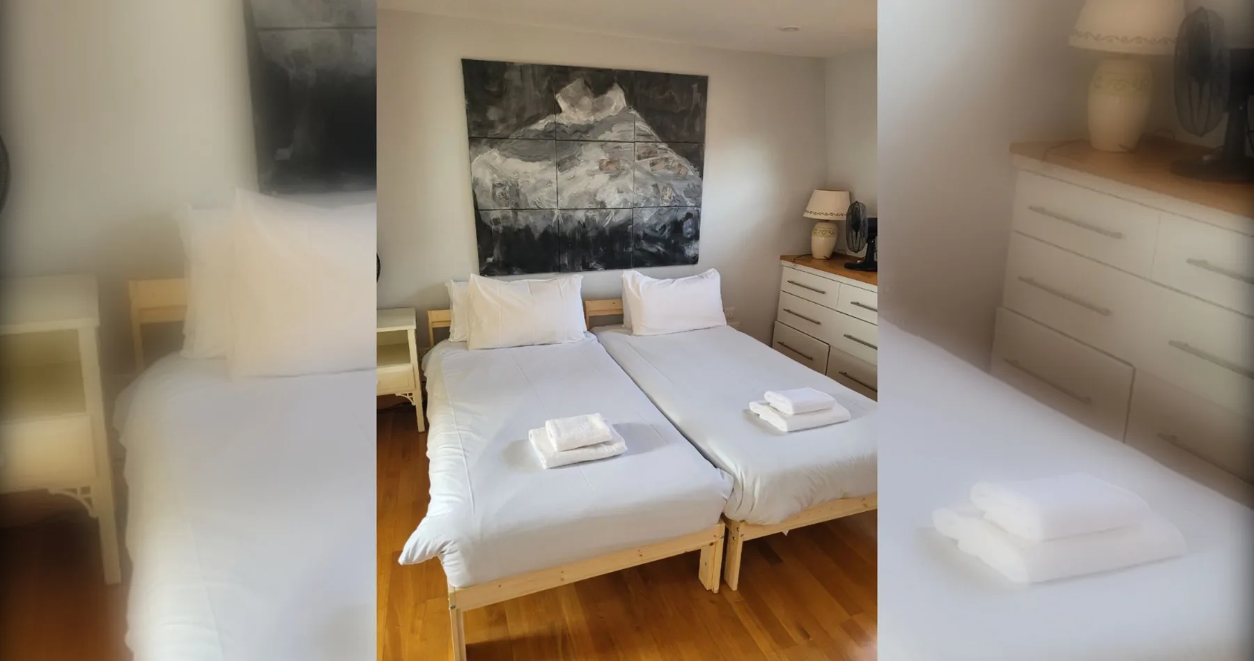 Un dormitorio con dos camas y una gran obra abstracta sobre ellas.