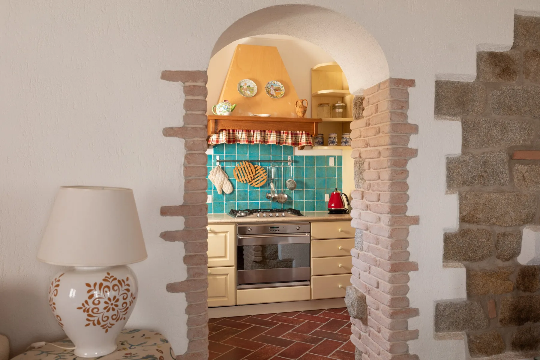 Una cocina compacta con azulejos turquesa y un arco enmarcado en ladrillo.