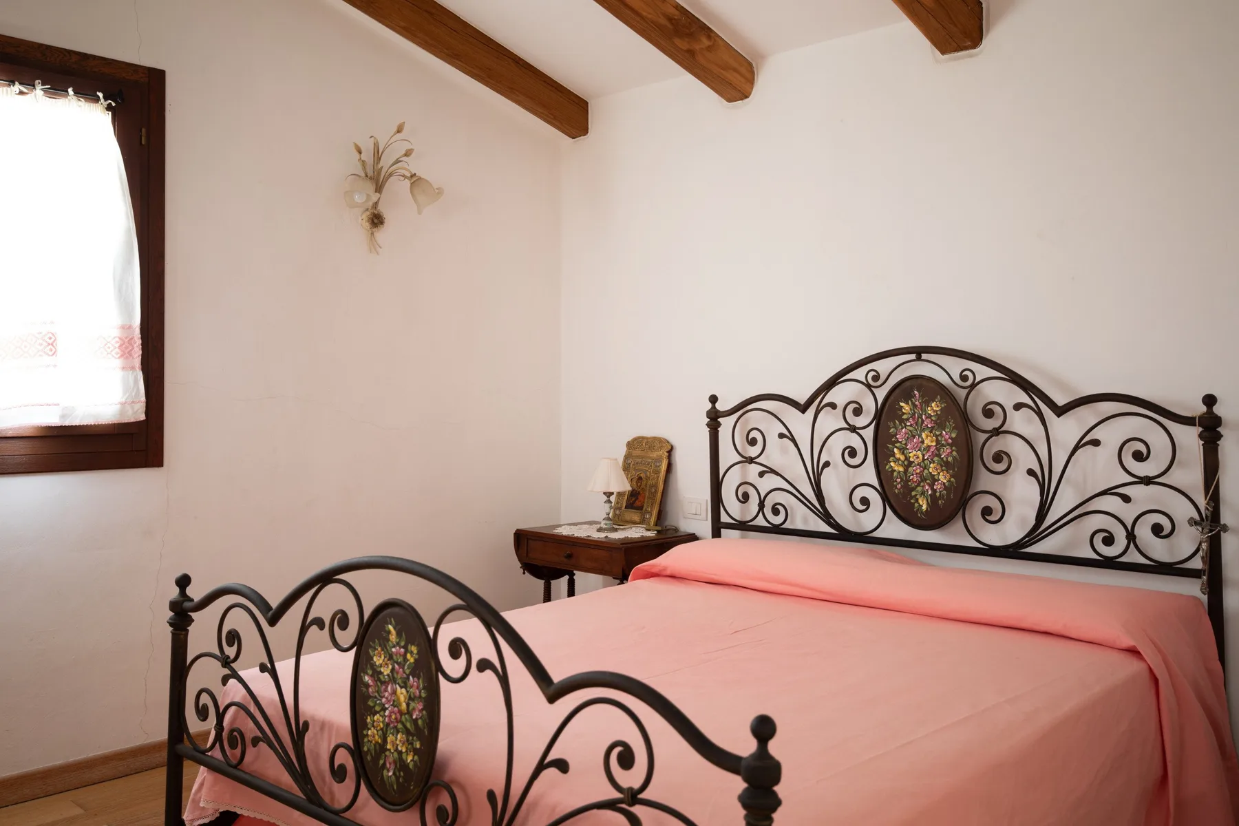 Un dormitorio con una cama rosa y un cabecero decorativo de metal oscuro.