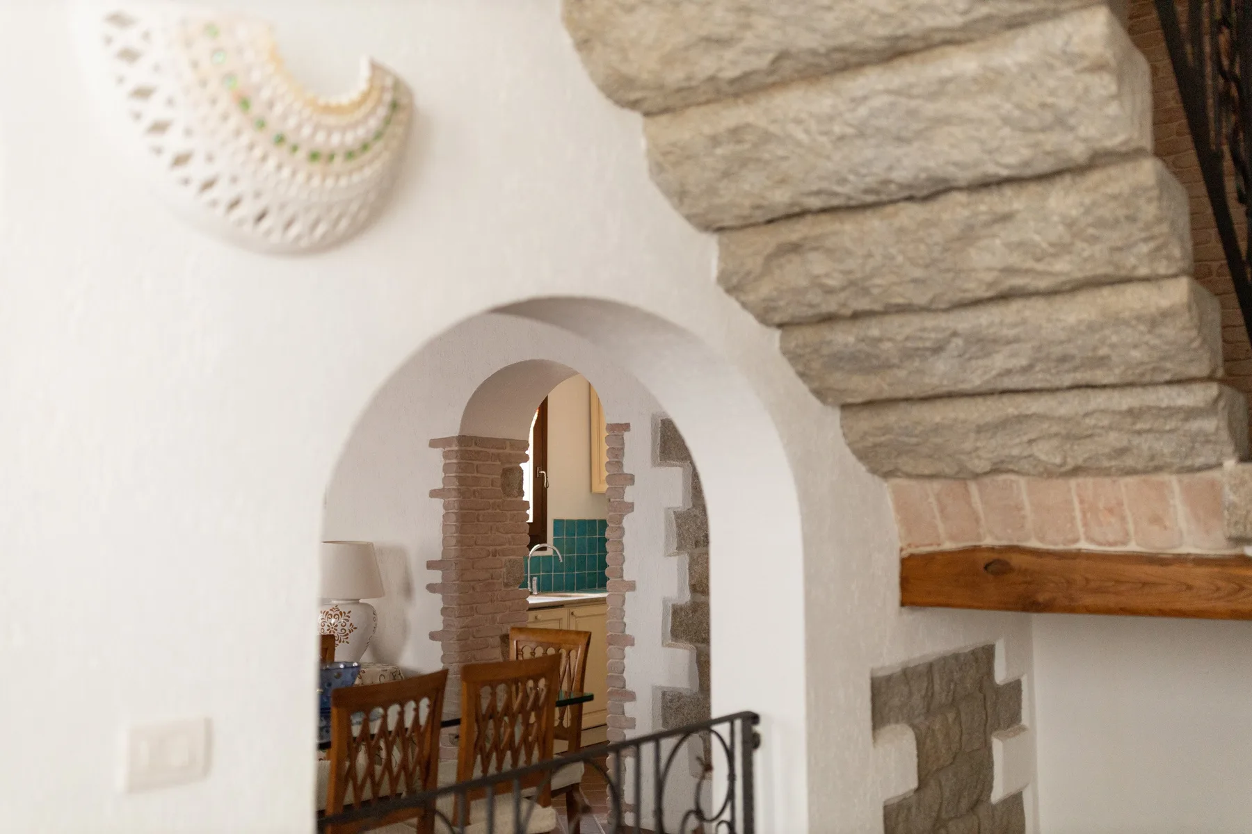 Un comedor con asientos de madera está junto a una puerta arqueada blanca.