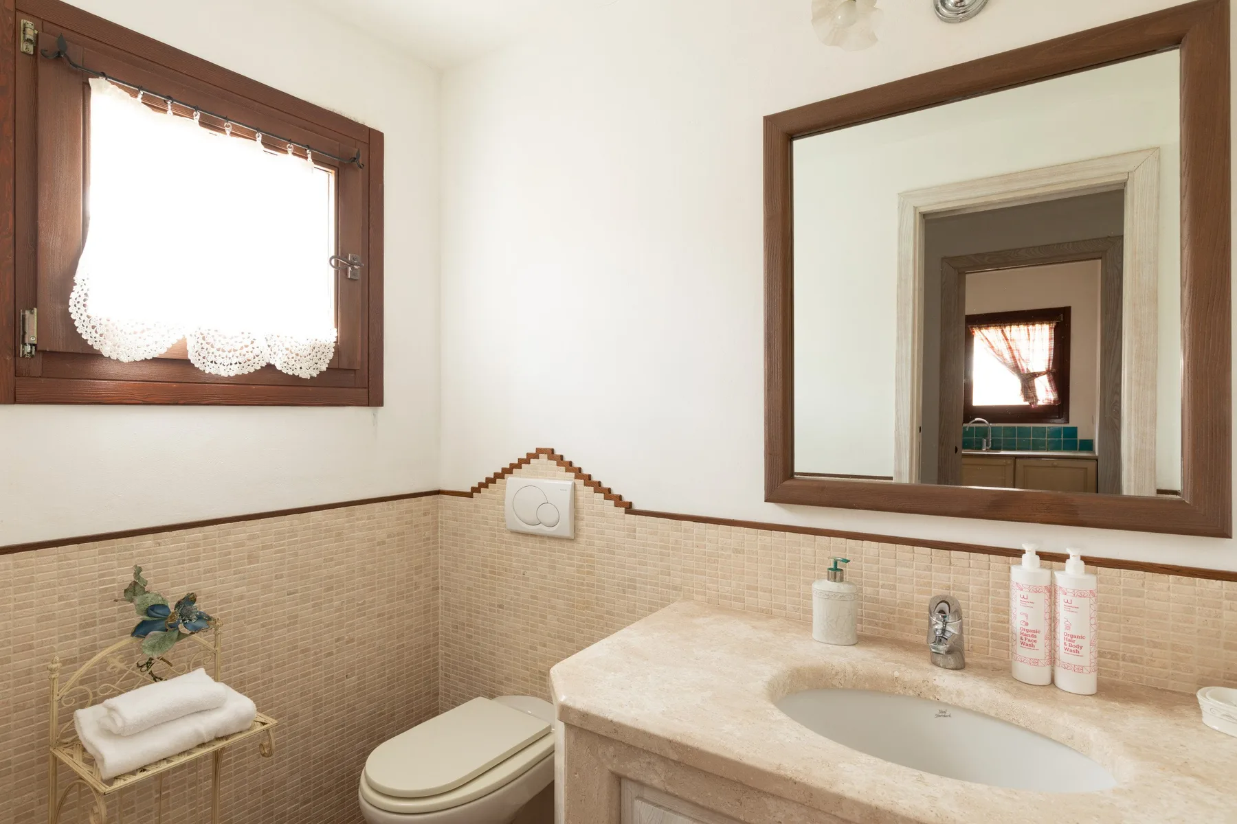 Un baño con lavabo, inodoro y un espejo grande en la pared.