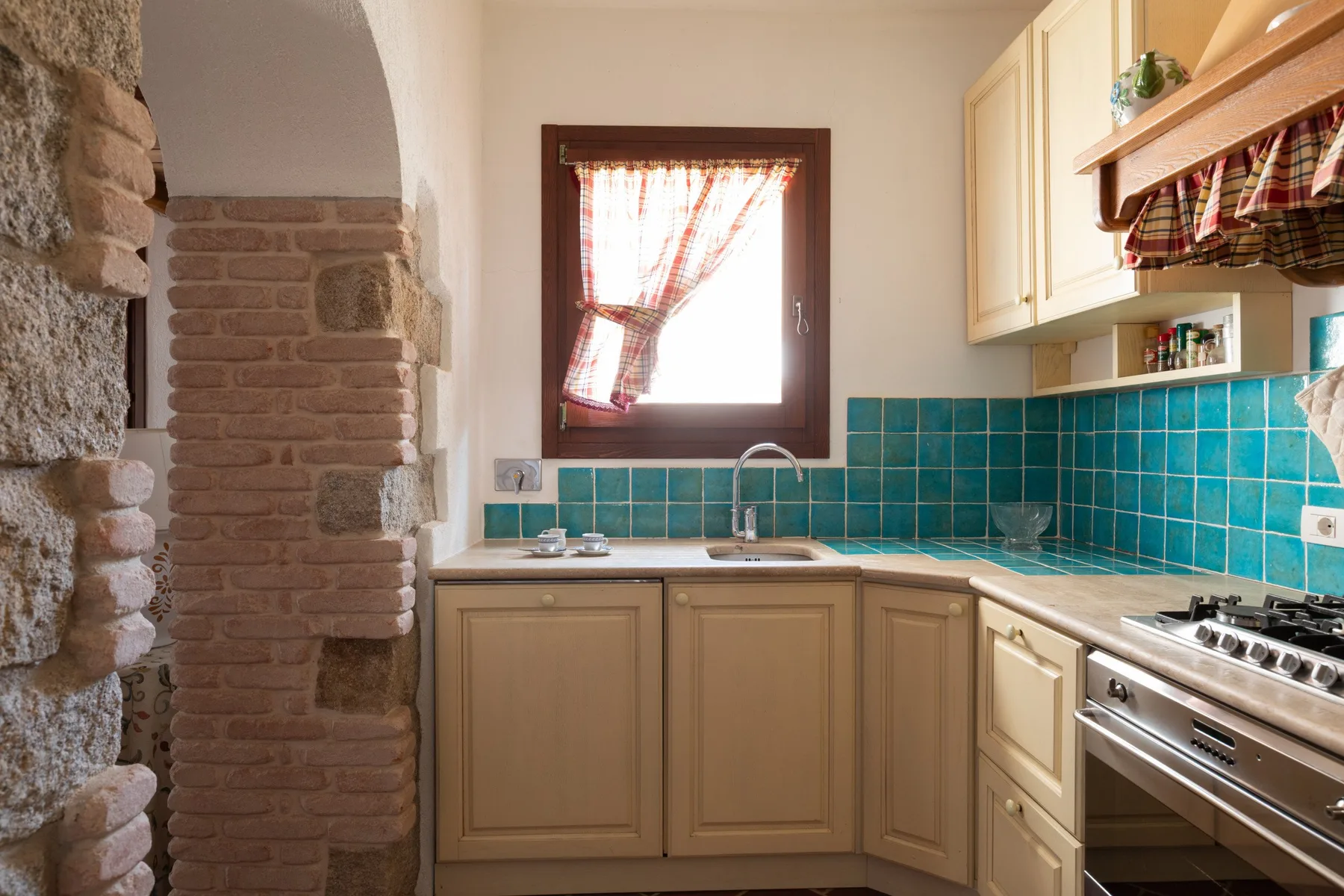 Una cocina con gabinetes claros, un salpicadero de azulejos y una ventana sobre el fregadero.
