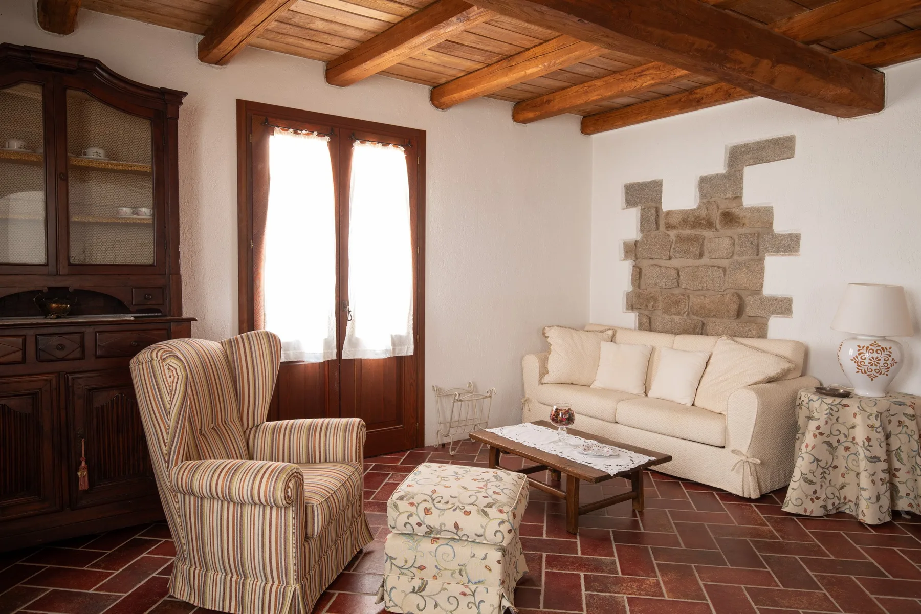 Una sala de estar con asientos color crema, un sillón estampado y vigas de madera expuestas.