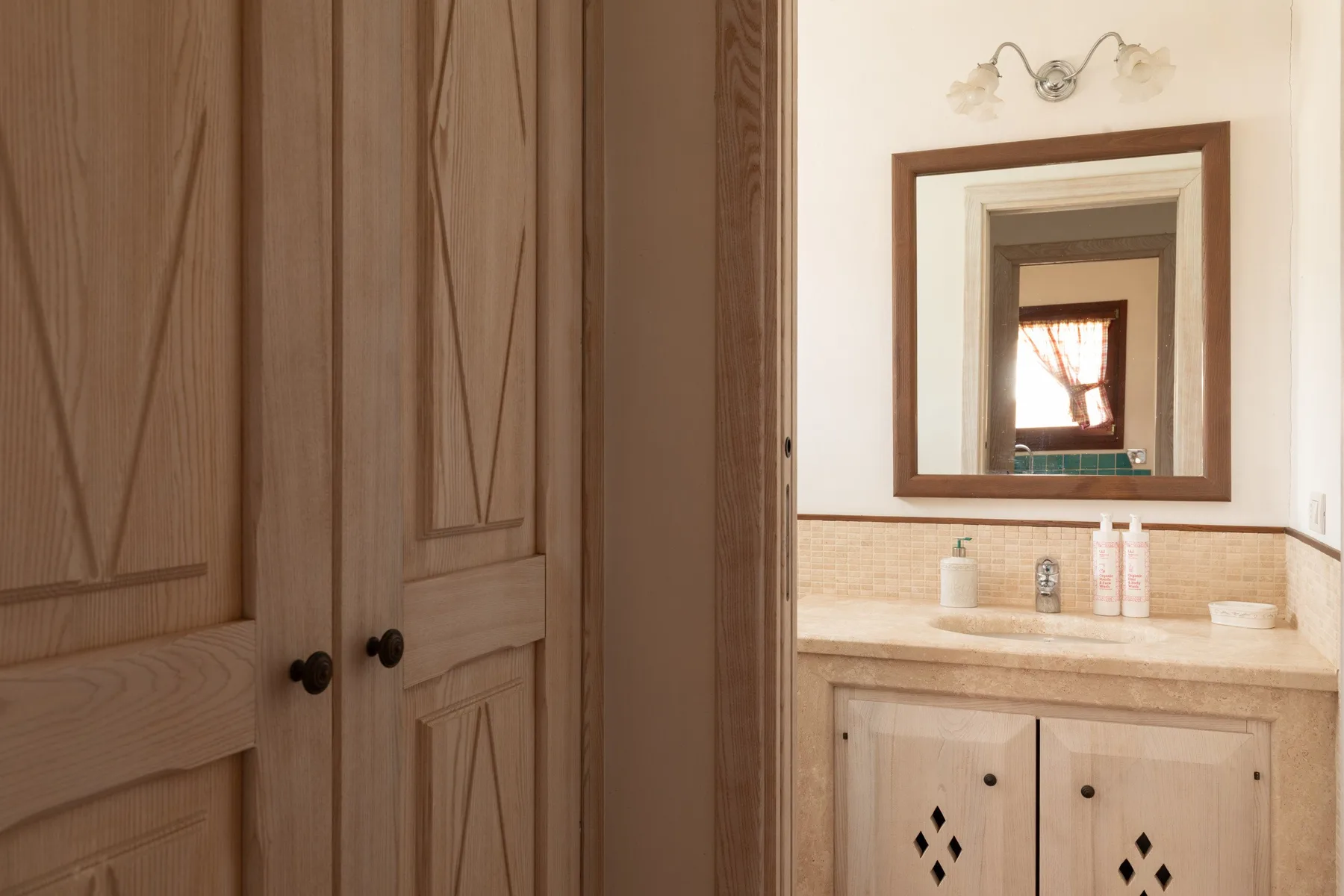 Un lavabo de baño con espejo está junto a puertas de armario de madera.