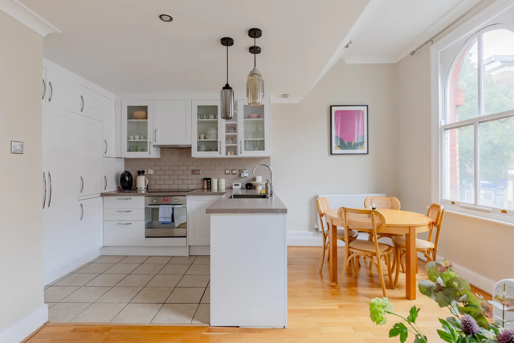A bright kitchen and dining area with white cabinets and a wooden table.