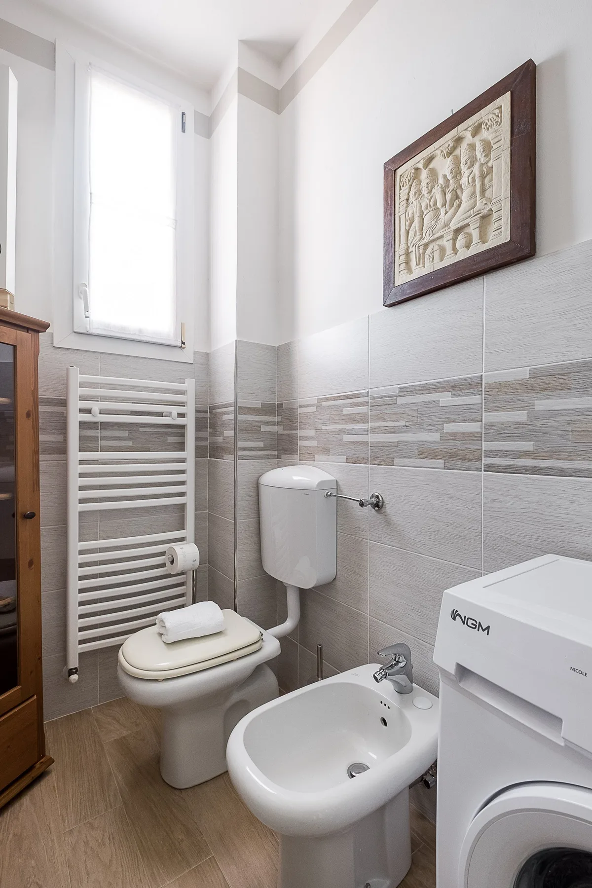A bright bathroom with a toilet, bidet, and washing machine.