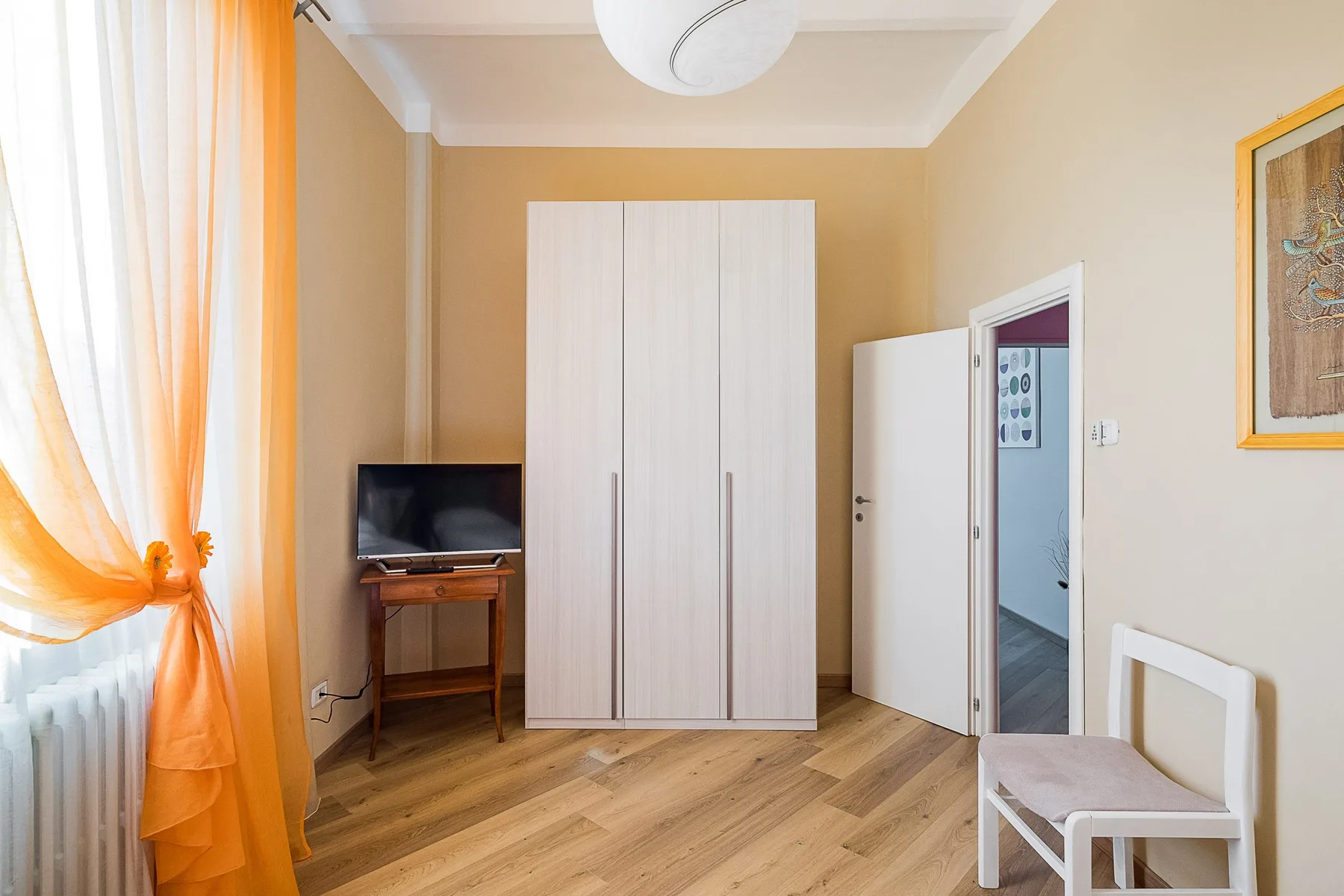 A bedroom with a wardrobe, television, and an open doorway.