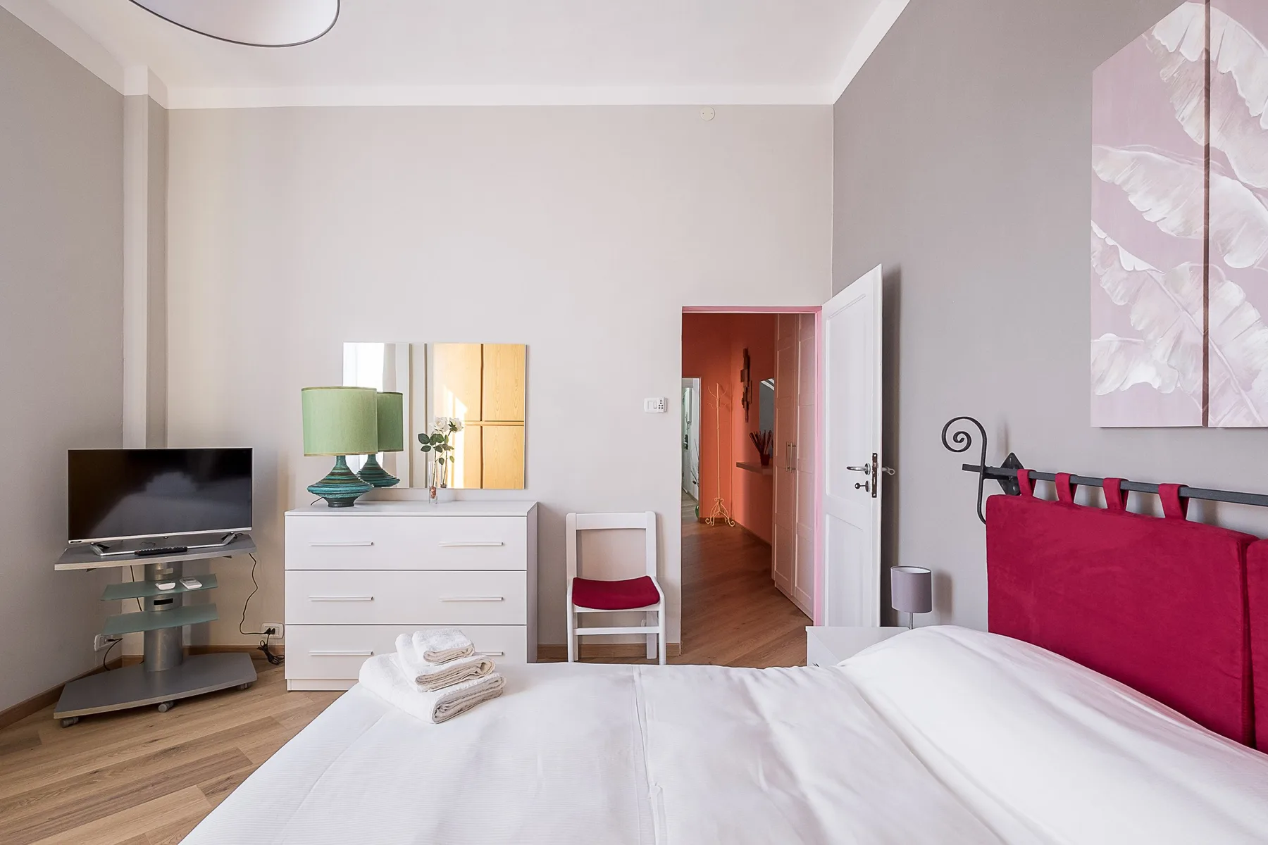A bedroom with a neatly made bed, dresser, and television.