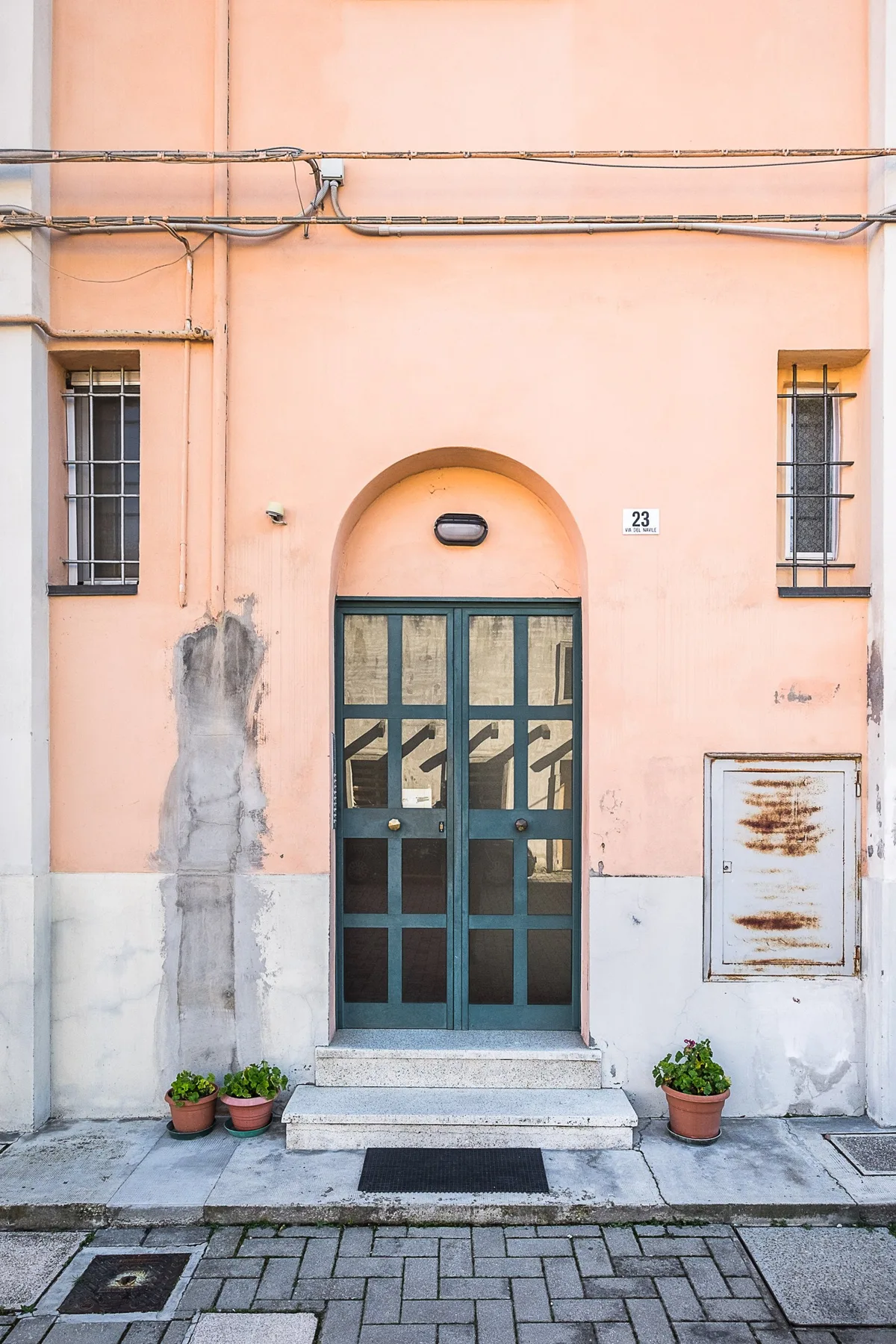 A peach-colored building entrance with a dark glazed door and barred windows.