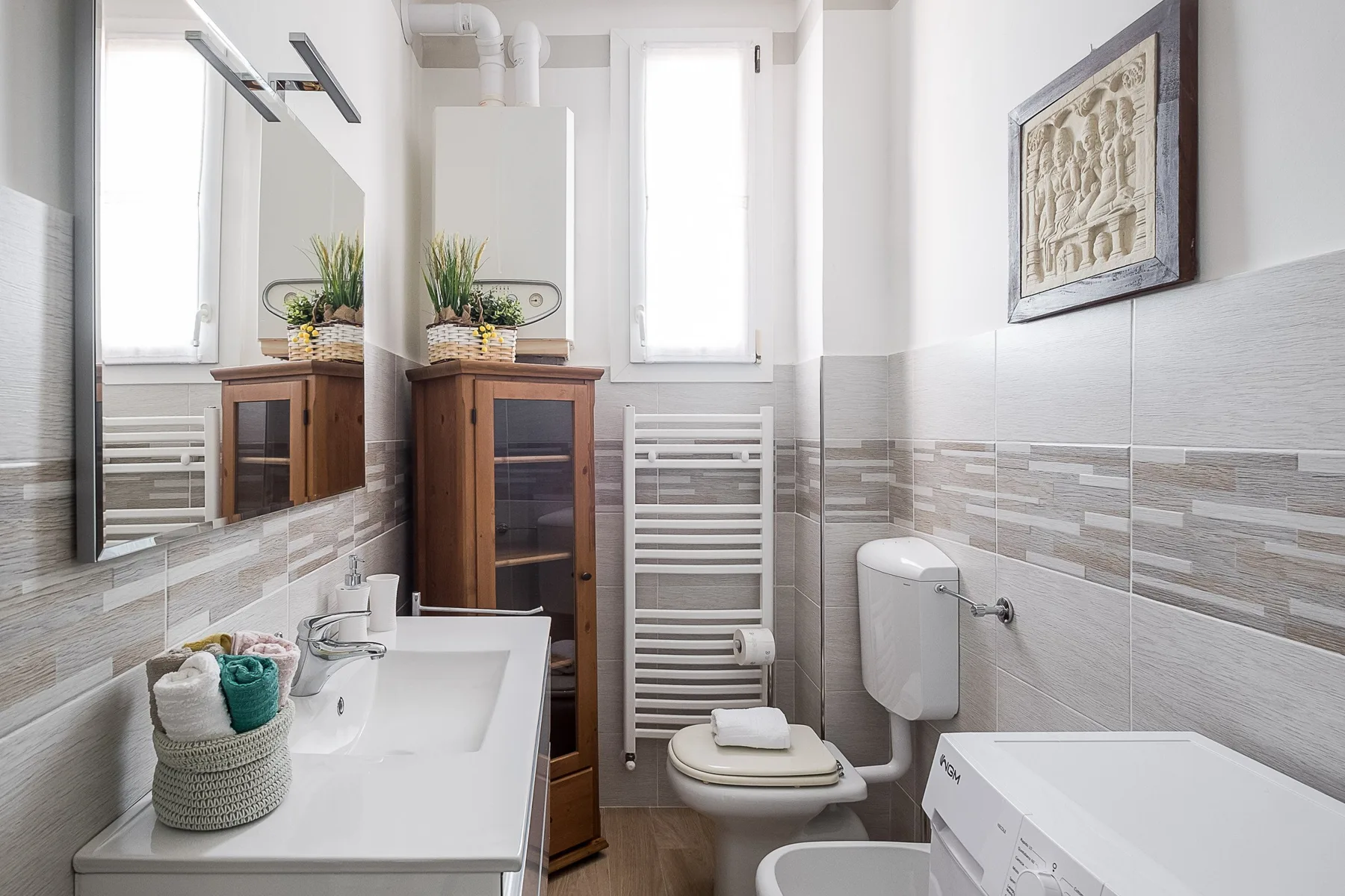 A bright bathroom with a sink, toilet, and washing machine.