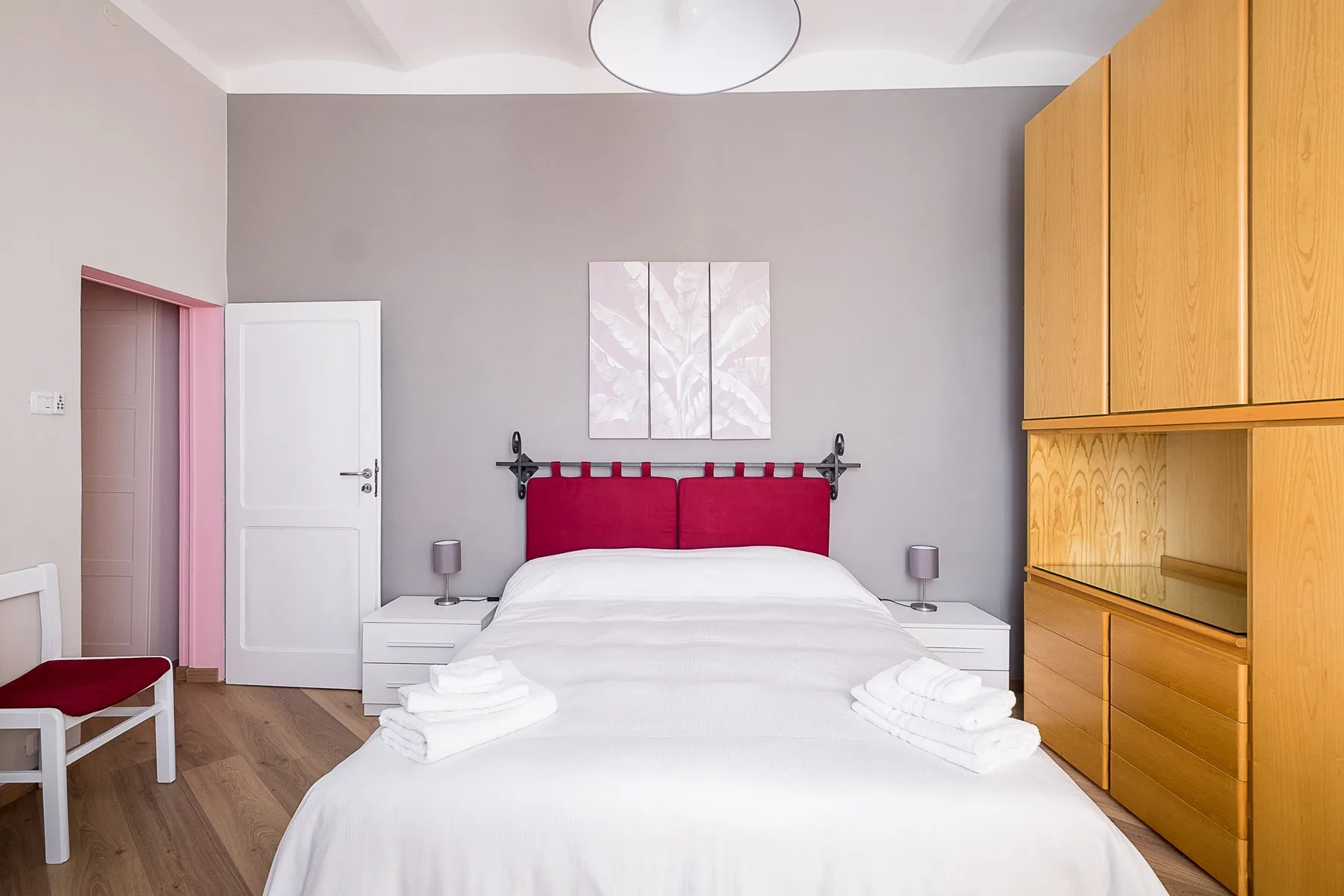 A bedroom with a neatly made bed and wooden built-in cabinets.
